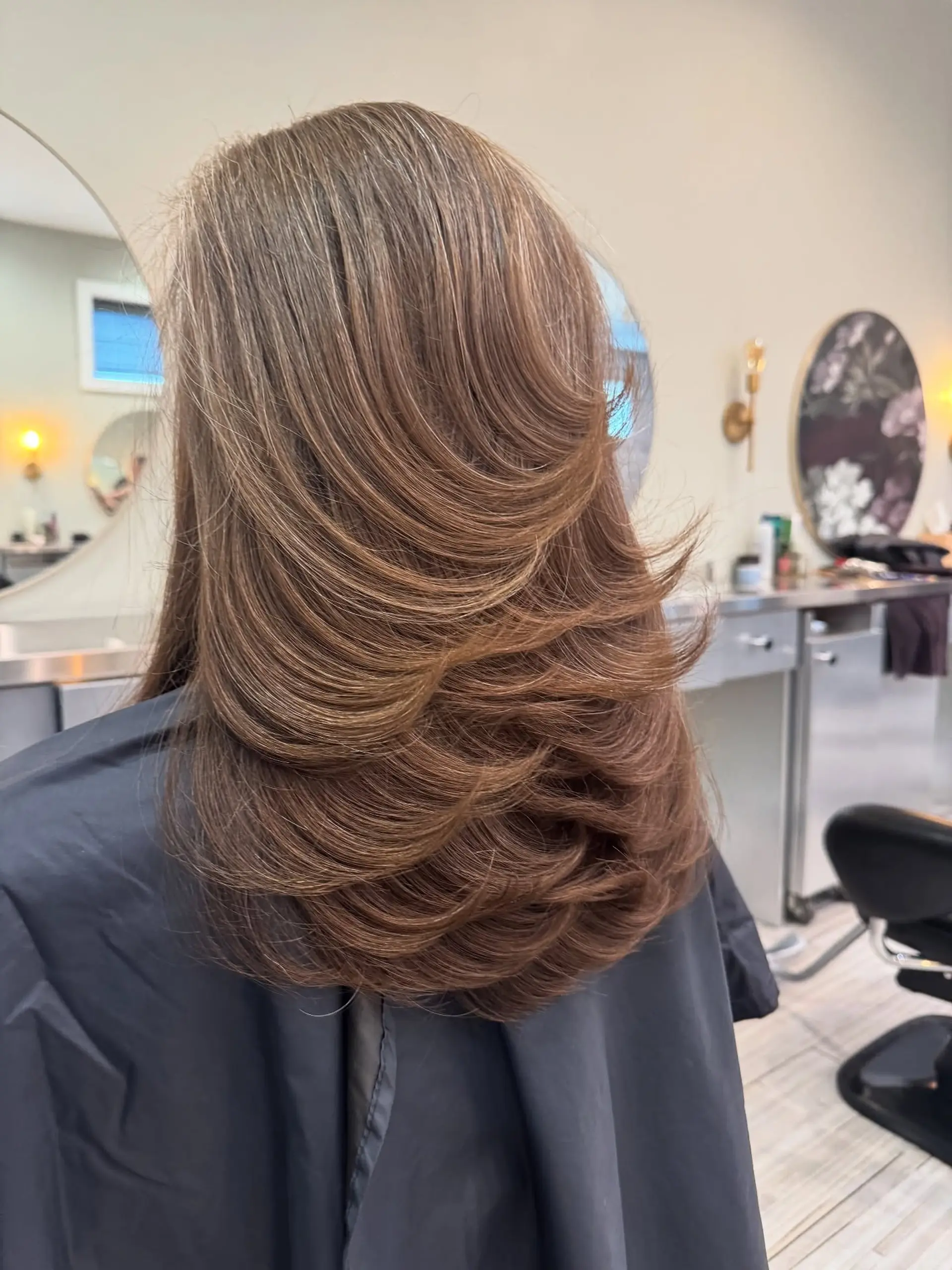 Long brown hair cut into dramatic, cascading tiers with bouncy, curled-under layers. 1
