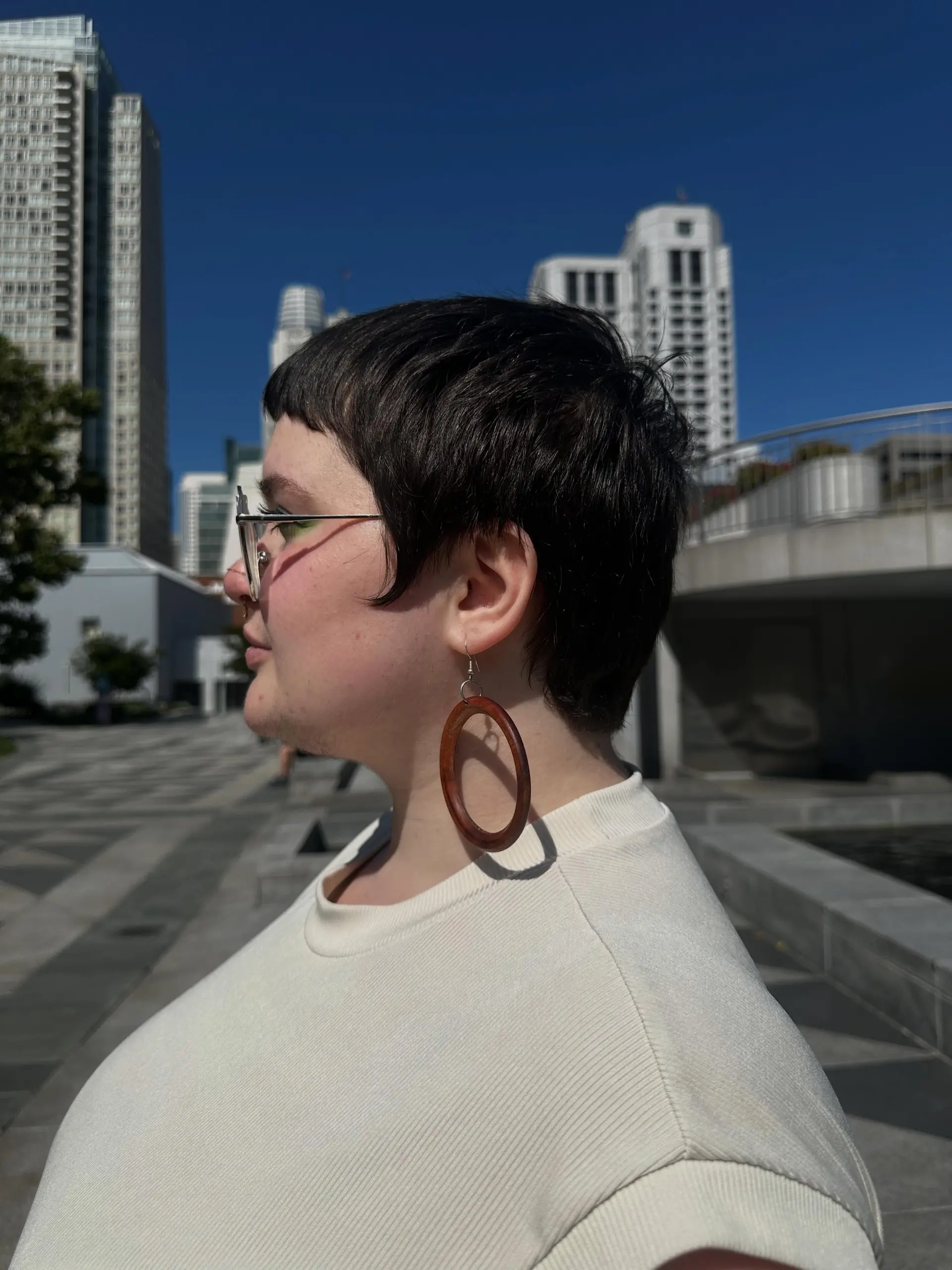 A short, textured pixie crop featuring blunt micro bangs and soft tapering around the ears. 1