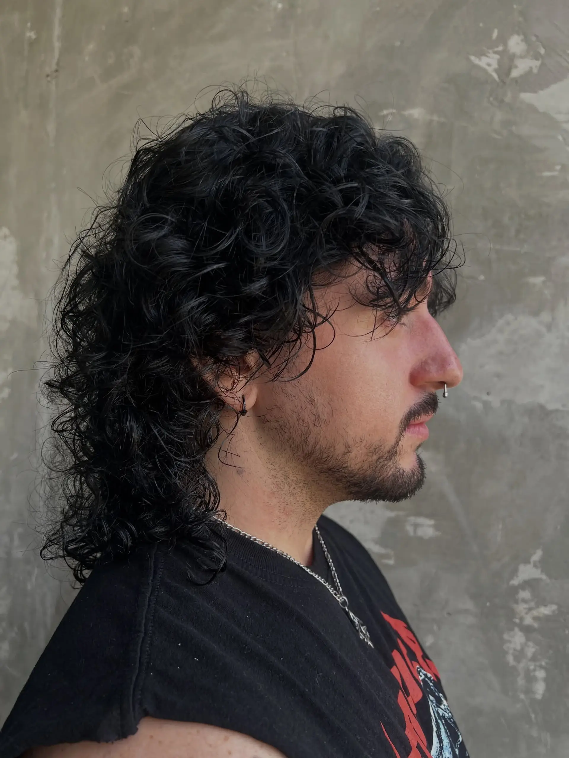 A textured curly wolf cut with layered volume on top, fringe falling across the brow, and longer cascading curls extending down the back in a modern shag mullet style. 1