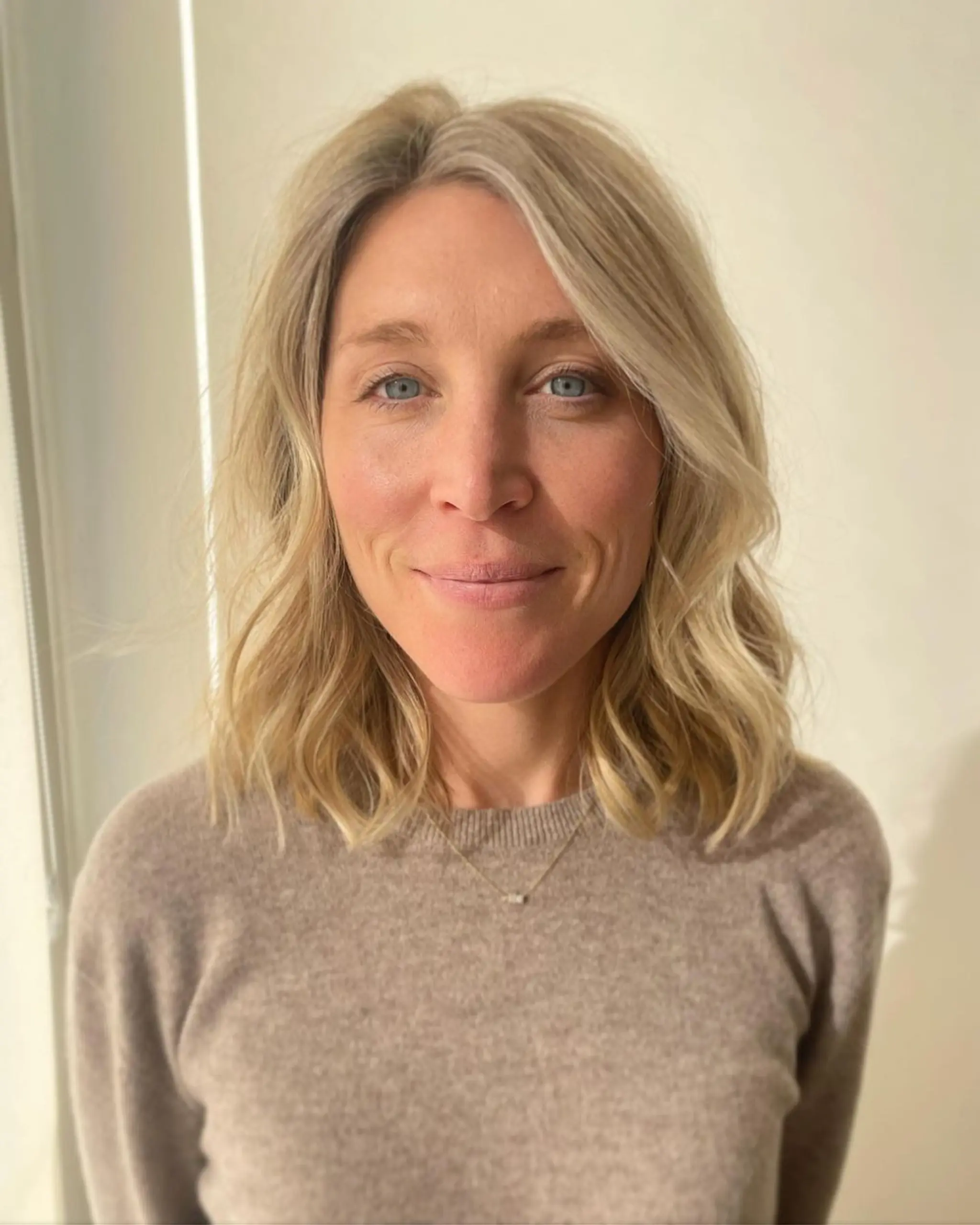 Medium-length wavy hair with soft waves and natural volume, blonde with platinum highlights, and a face-framing layered structure.