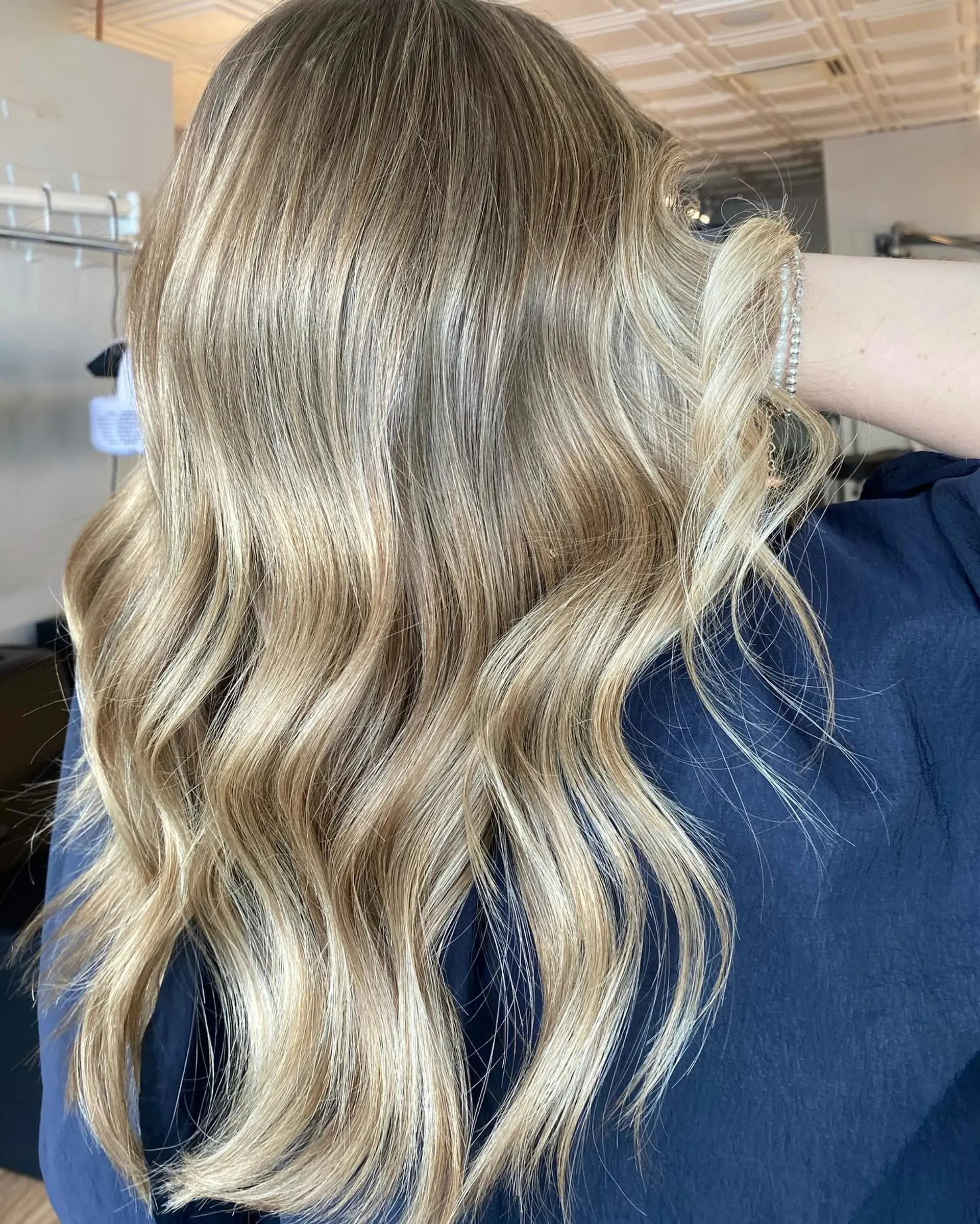 Long multi-dimensional sandy blonde hair styled in soft, loose waves. 1
