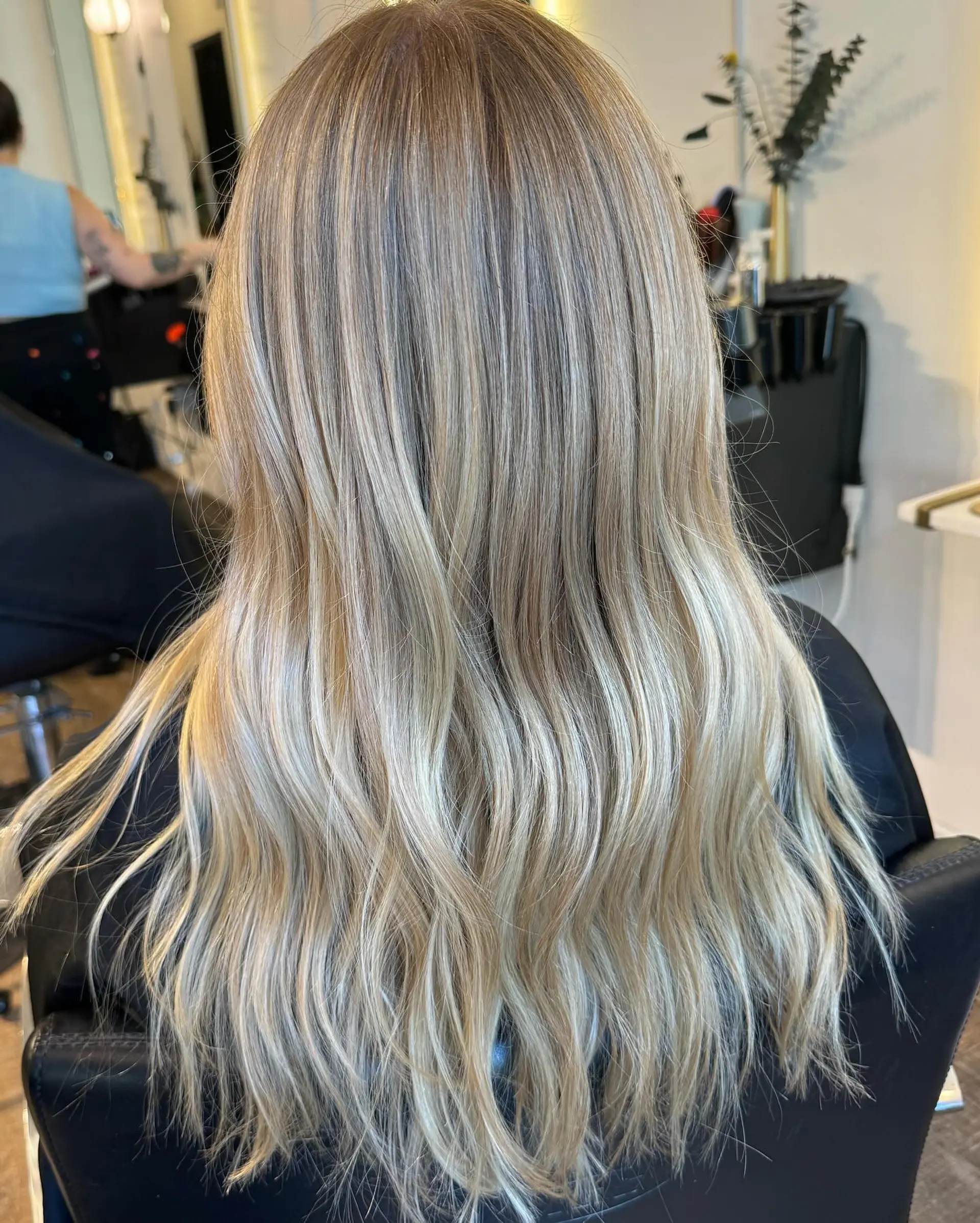 Long hair featuring finely blended dimensional blonde highlights with soft, lived-in waves. 1
