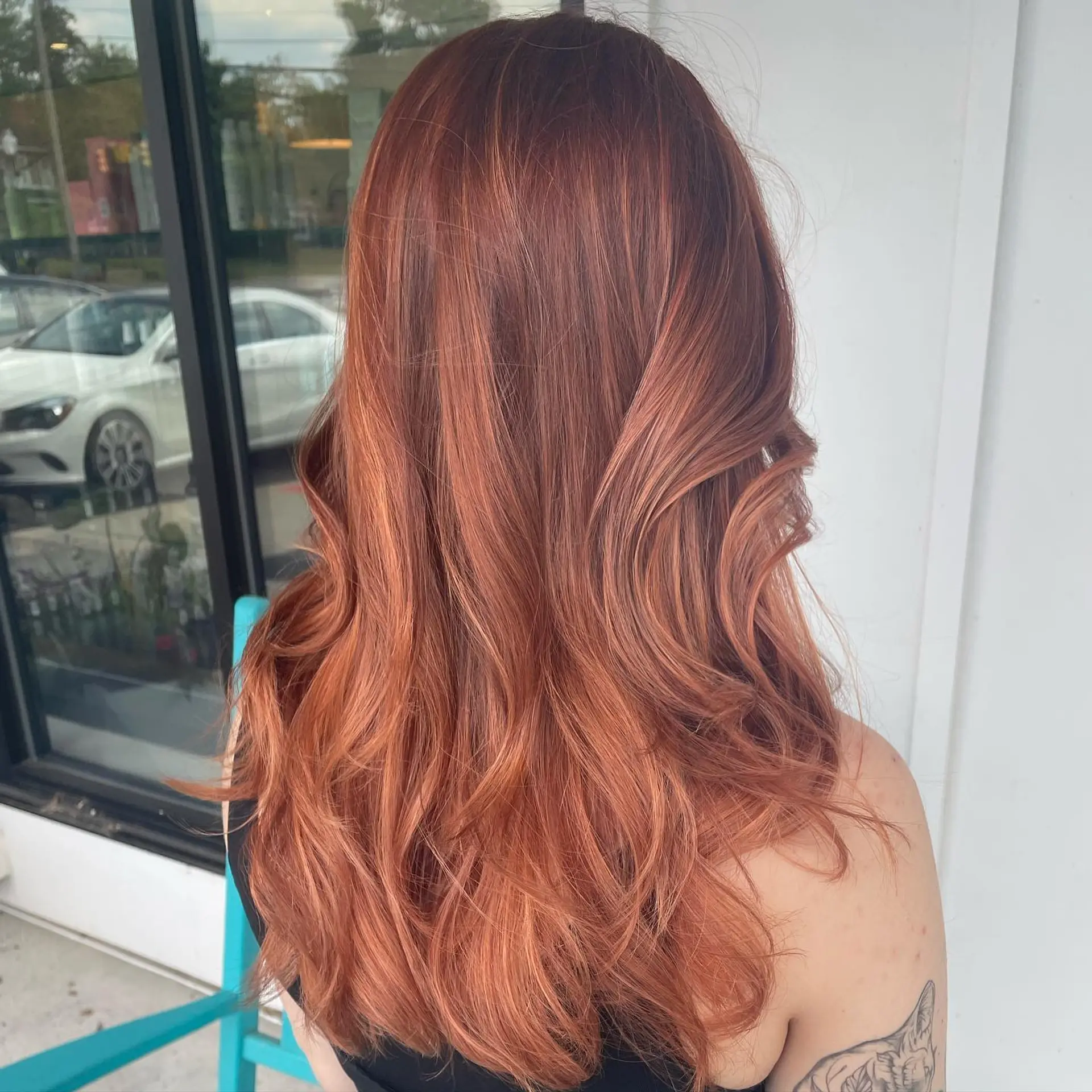Long wavy hair colored in a blend of peachy rose gold and warm copper tones. 1