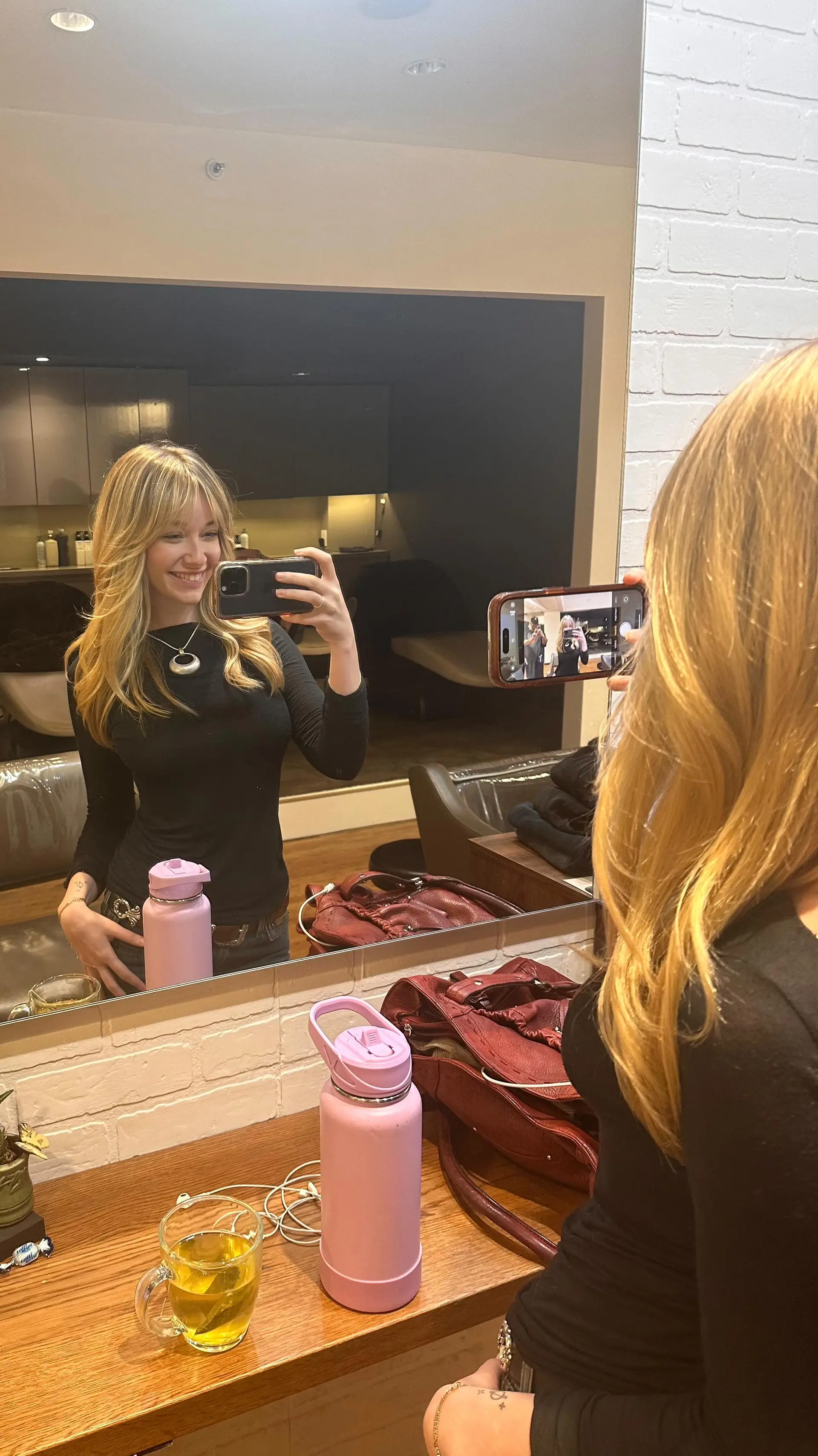 A long, voluminous golden blonde blowout featuring soft face-framing layers and wispy curtain bangs. 1