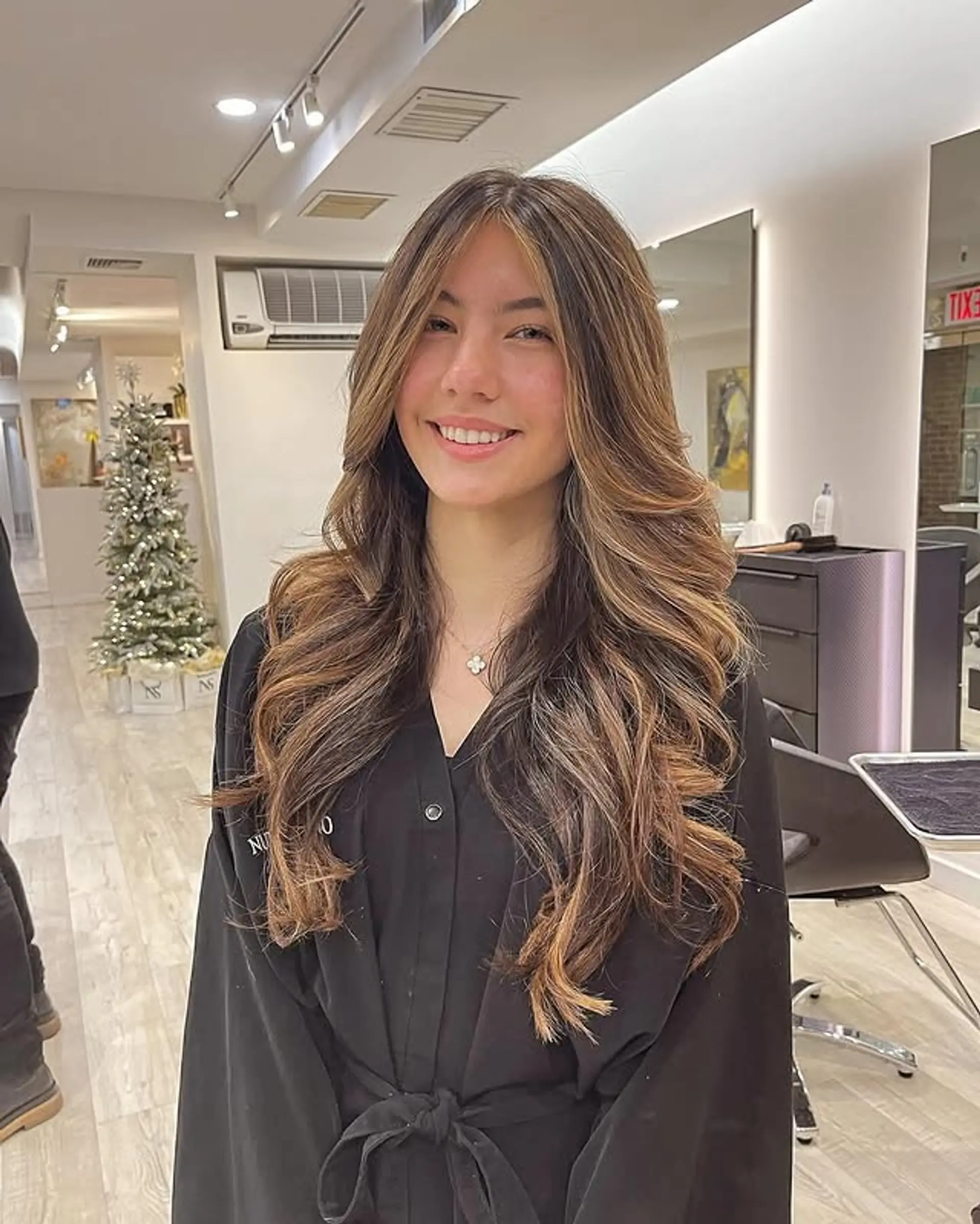 A long, layered cut with a beautiful bronde balayage that enhances the natural wave and creates a dimensional, stylish look. 1