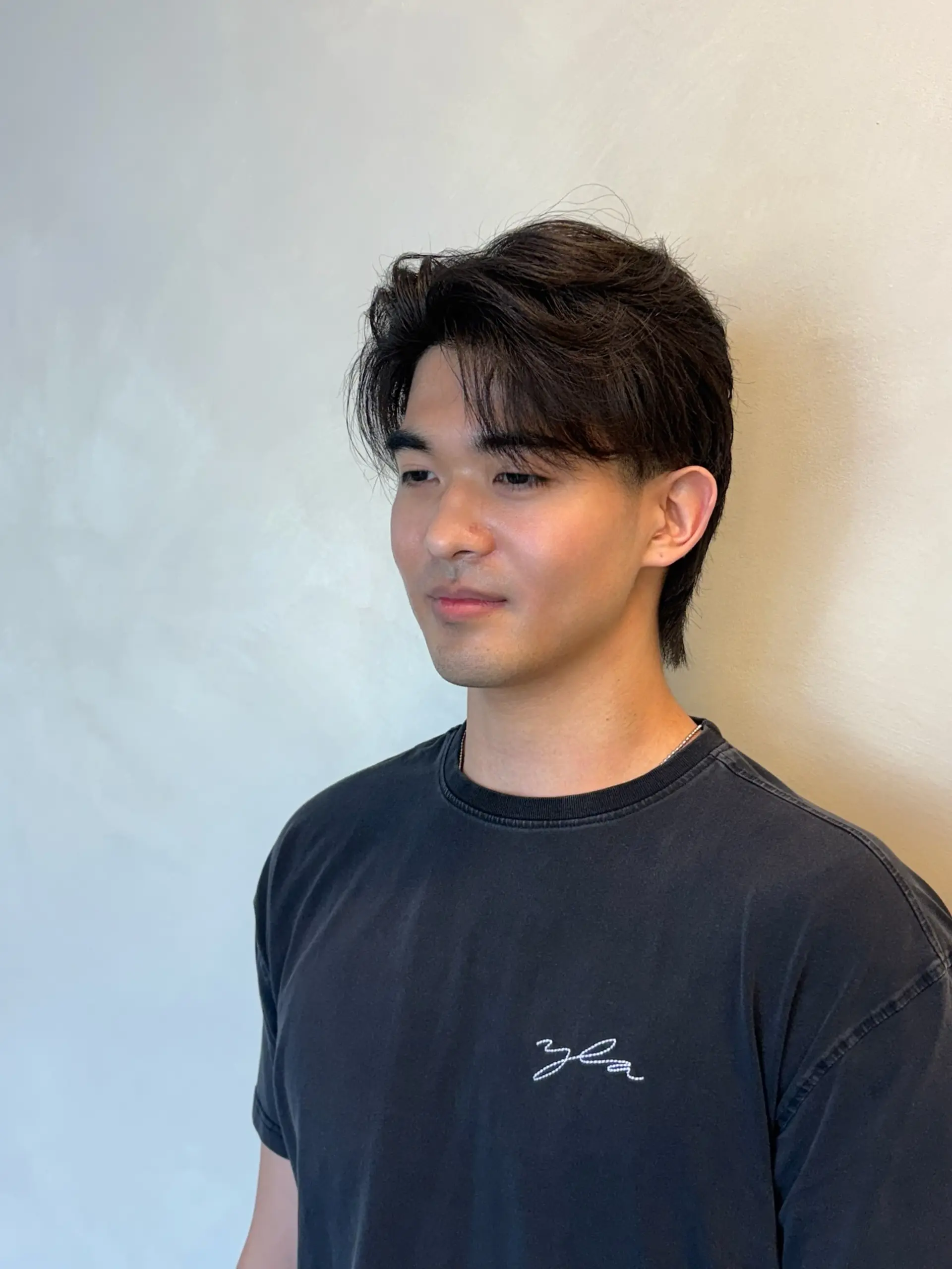 Modern men's haircut with soft parted curtain fringe and textured layers tapering down the back. 1