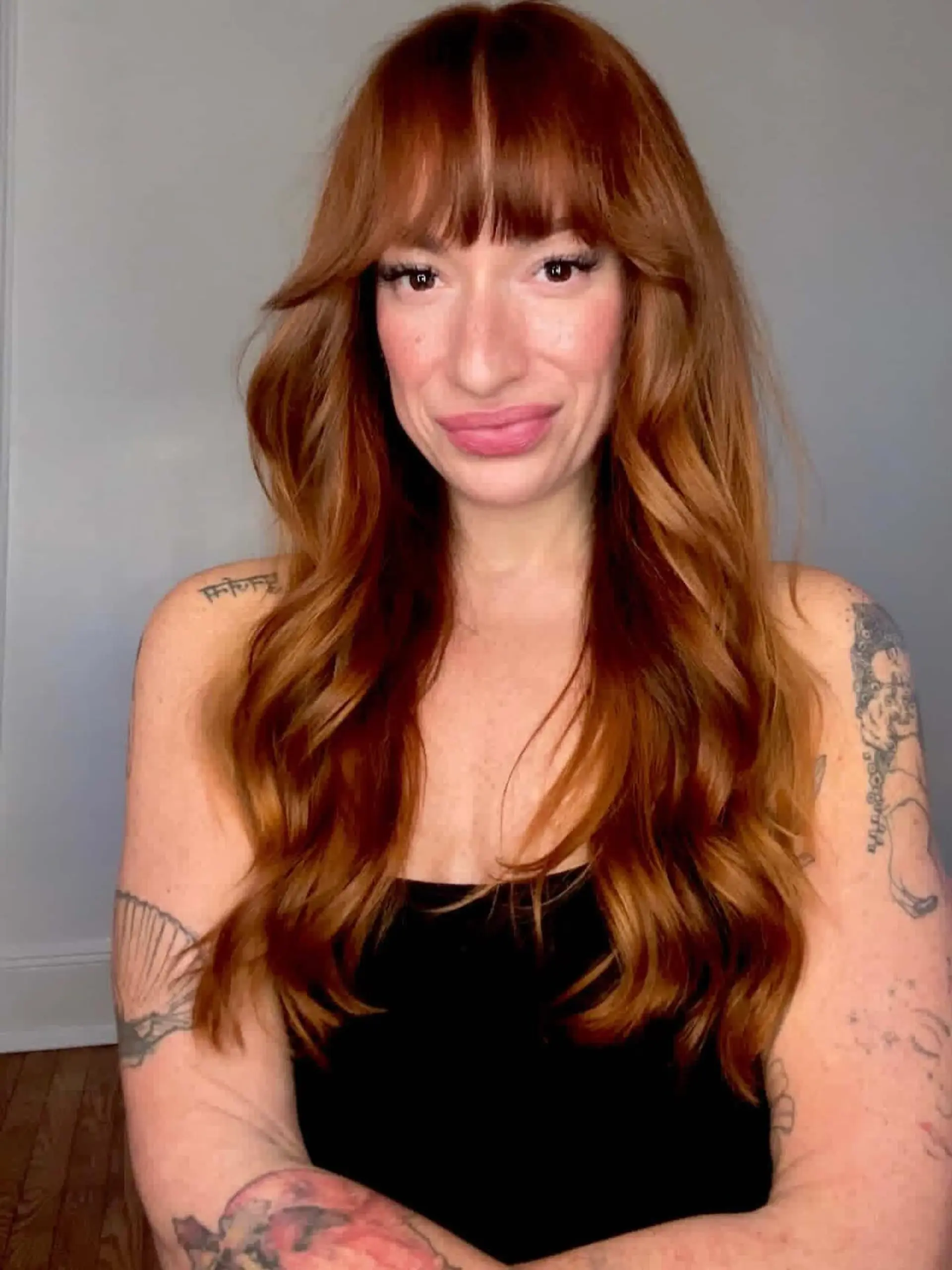 Long copper hair styled with soft, loose waves and full fringe bangs. 1