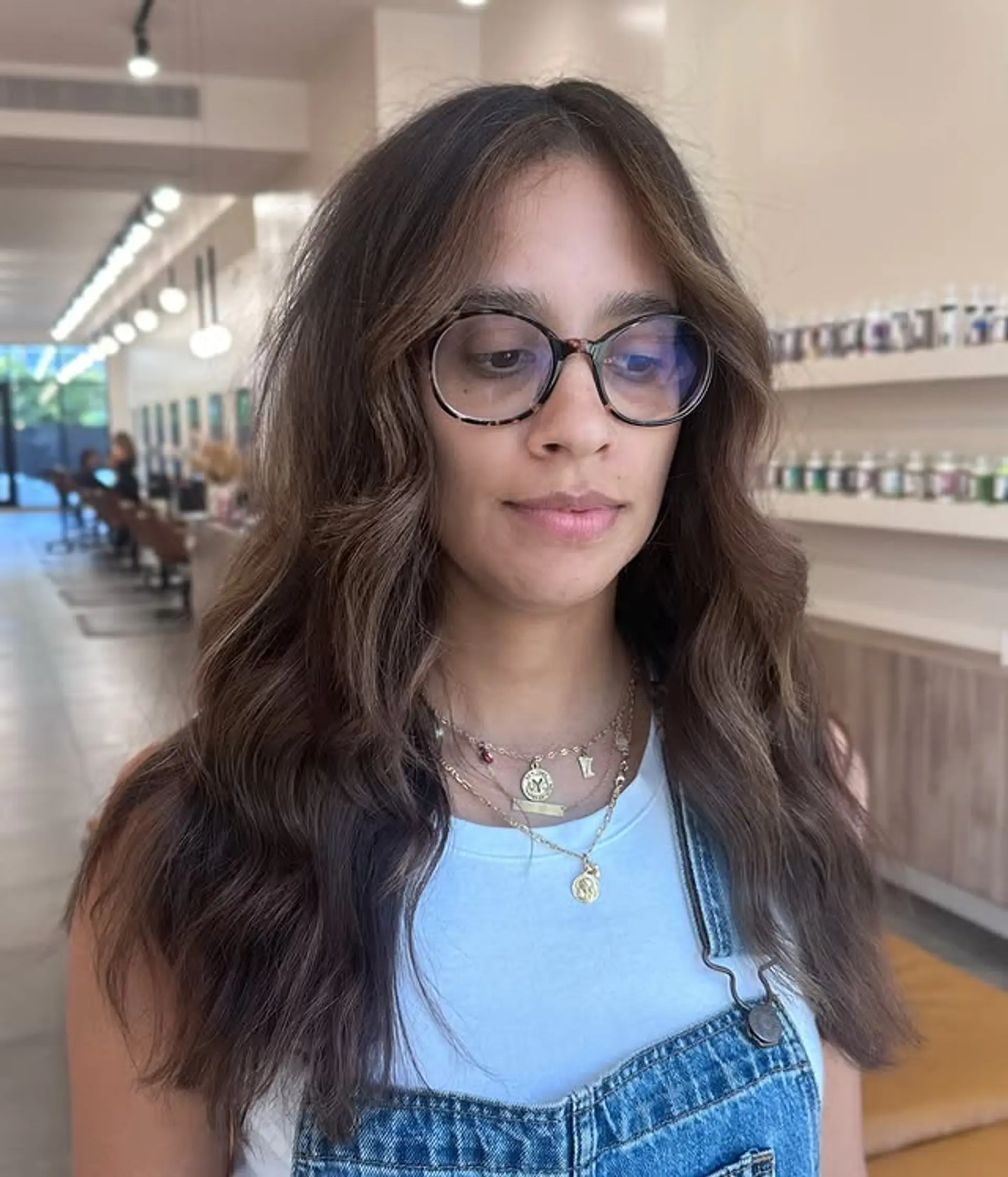 Wavy medium-length hairstyle with face-framing layers and a soft, natural wave pattern. 1