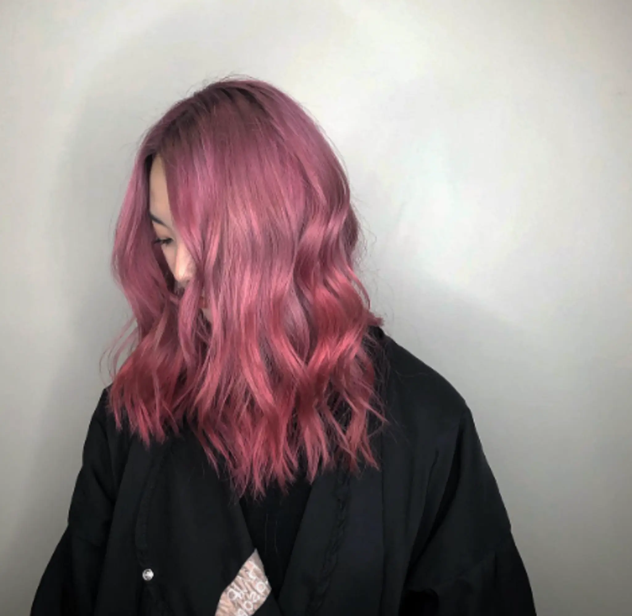 Pastel pink, medium-length, wavy hair with soft, voluminous waves and a middle part.