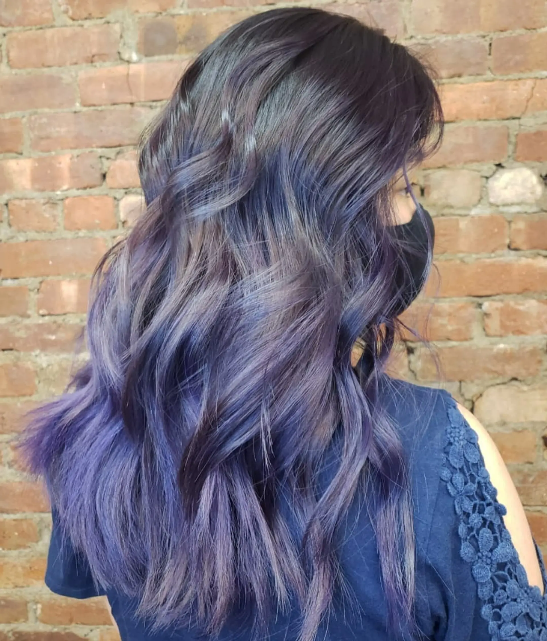 Long wavy hair featuring a vibrant violet and smoky blue balayage gradient over dark roots. 1