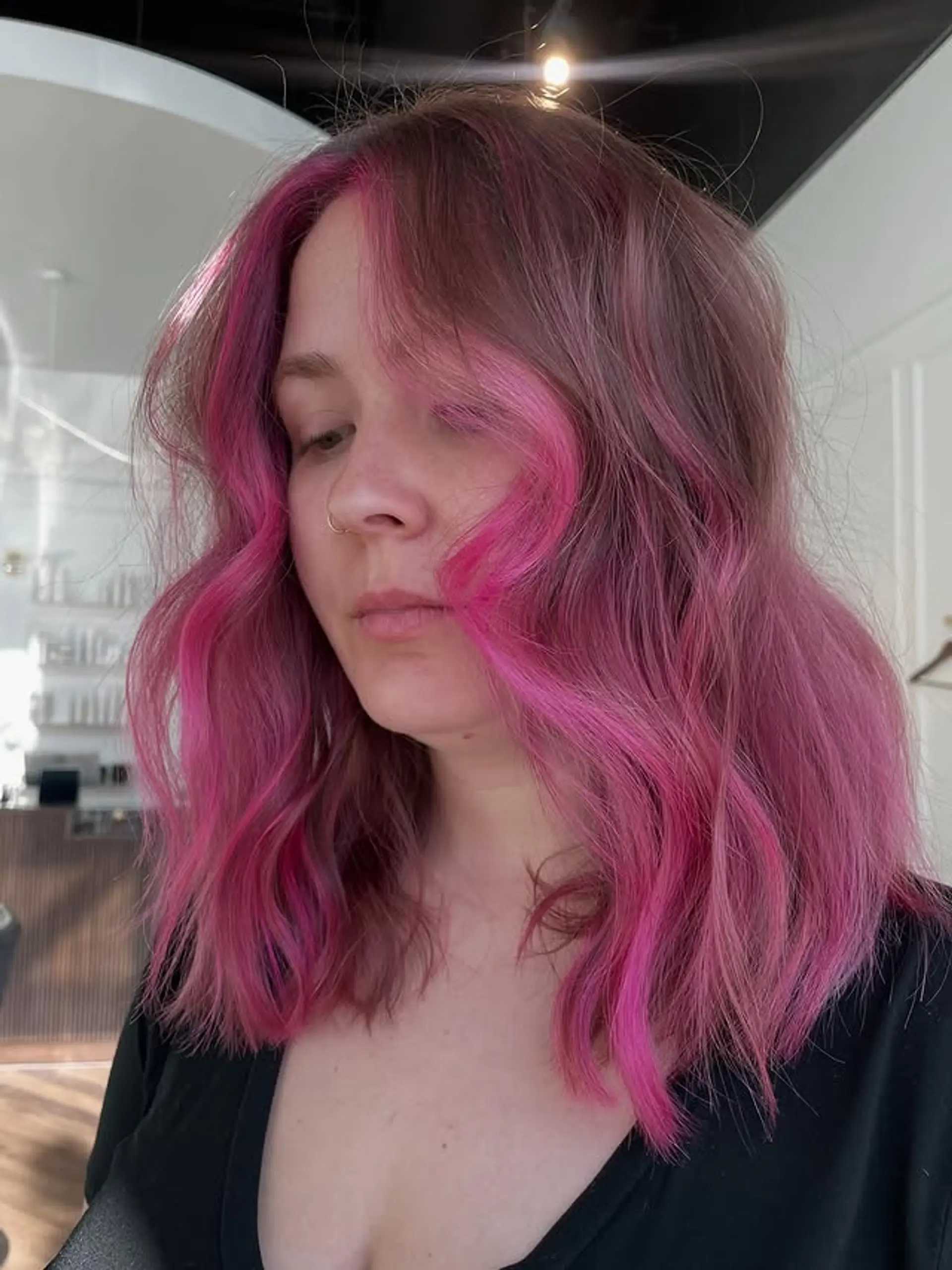 A medium-length wavy hairstyle featuring striking neon pink money piece highlights. 1