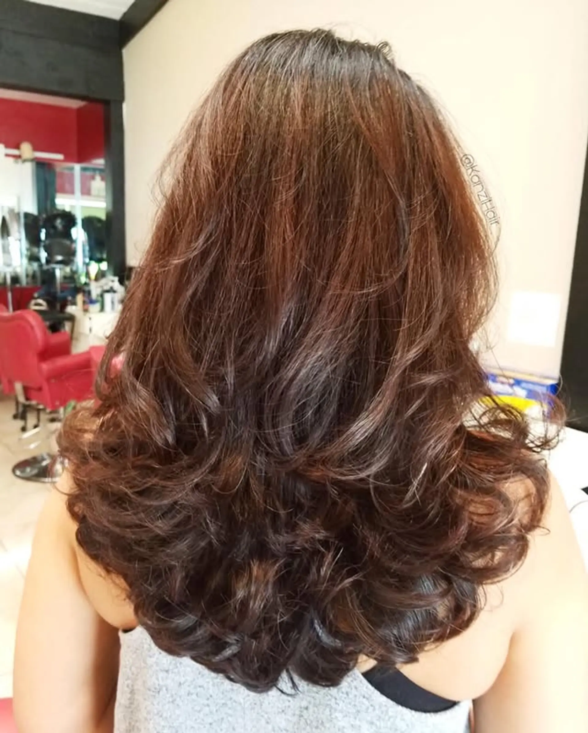 This stunning hairstyle features voluminous, bouncy curls with distinct layers that add body and movement. The ends are beautifully curled, creating a soft, full silhouette. The layering throughout enhances the natural texture and adds dimension. 1