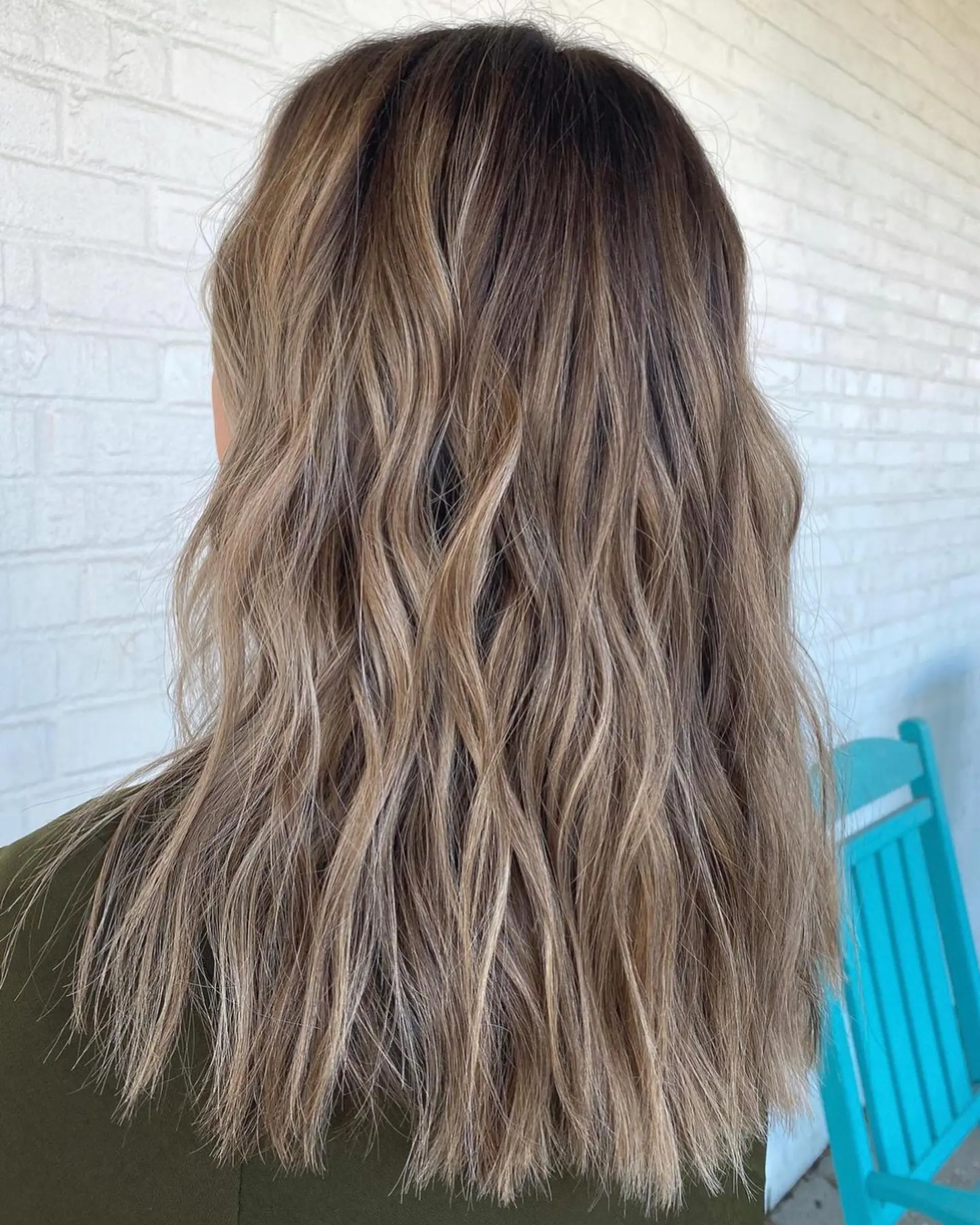 Long bronde hair featuring soft, beachy waves with a seamless blend of brunette and blonde dimensional highlights. 1