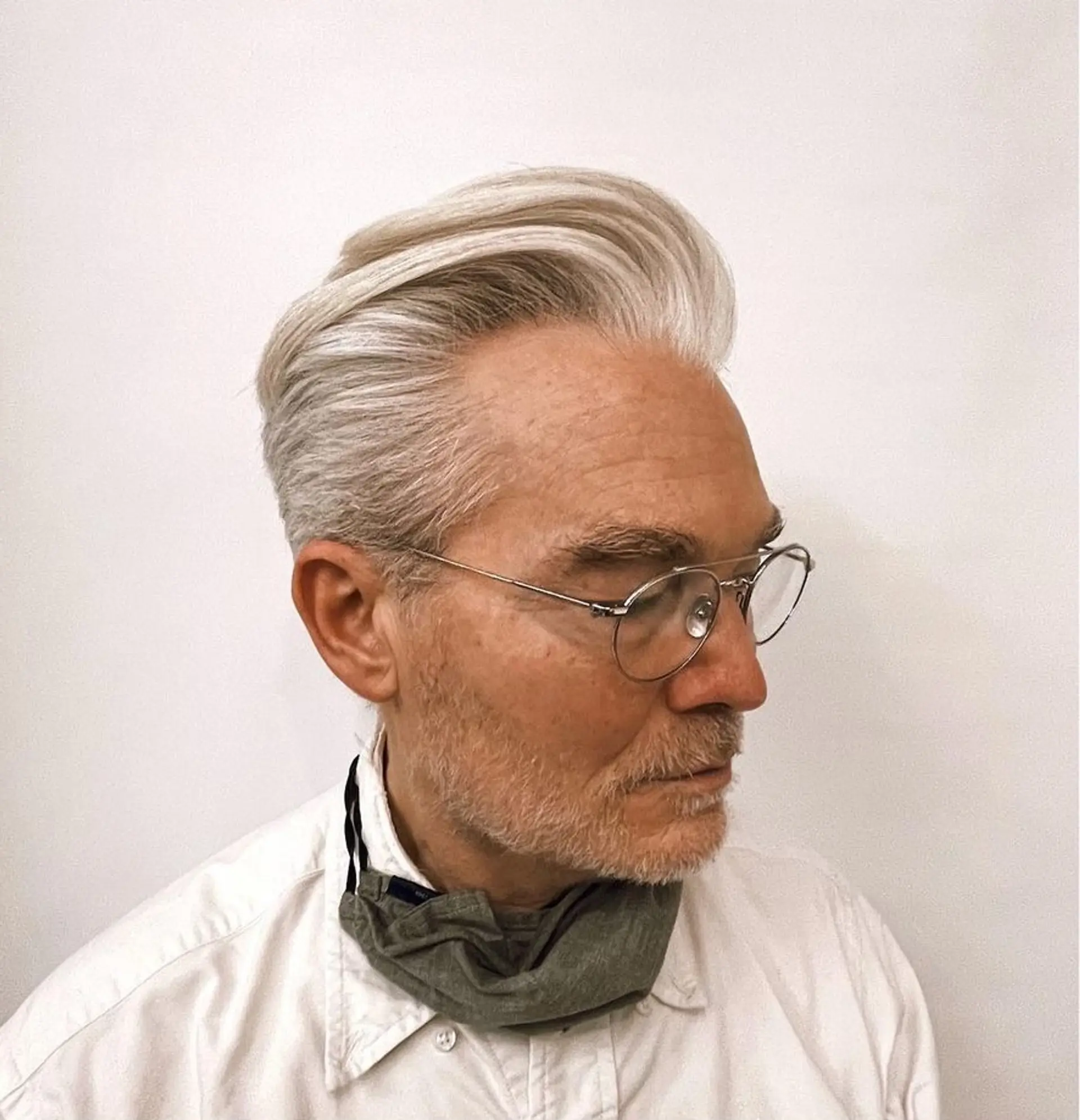 A sophisticated silver pompadour with a sleek finish, medium length and straight texture, swept back with considerable volume, creating an elegant and poised appearance. 1