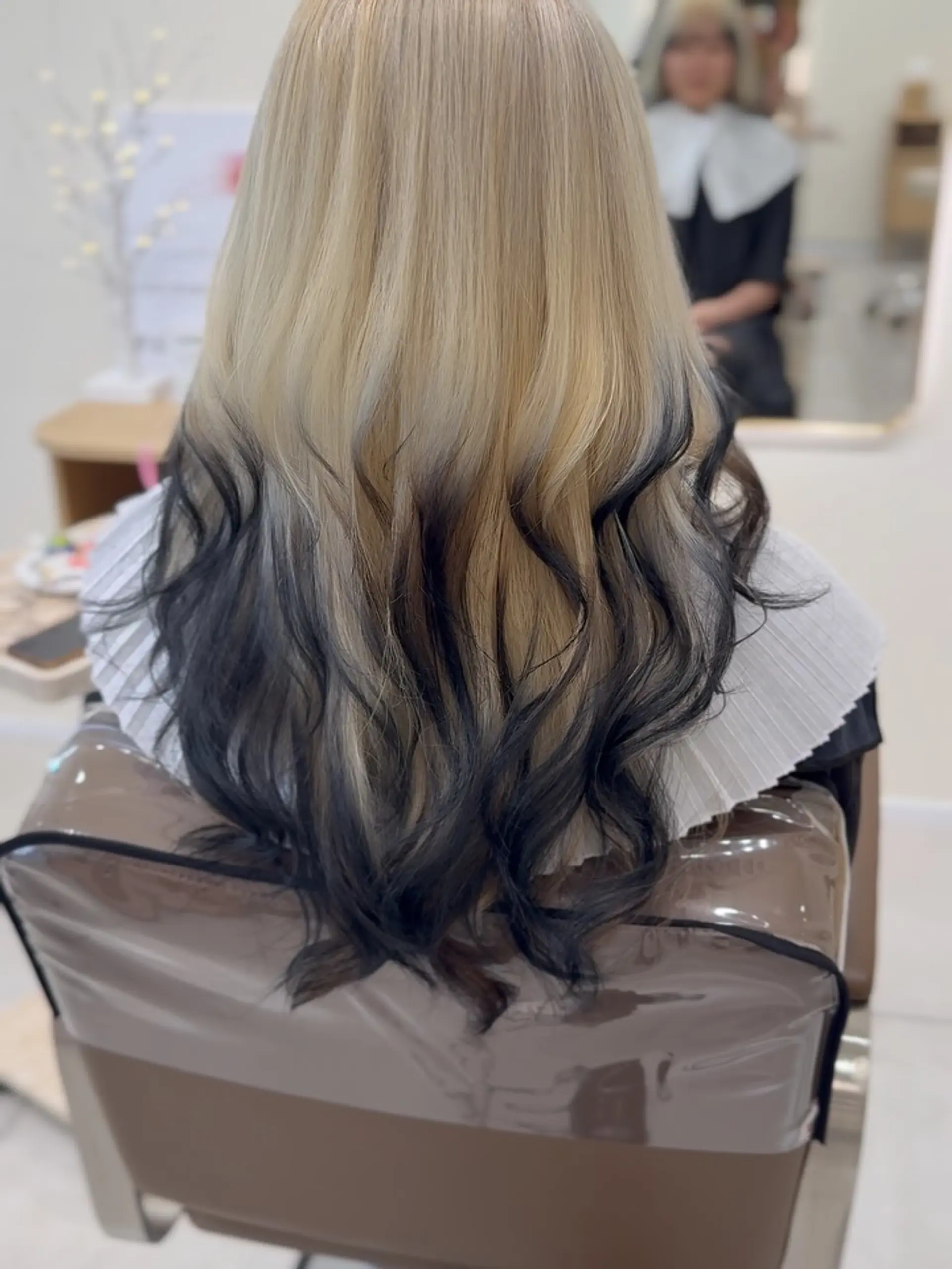 Long wavy blonde hair finished with striking black dip-dyed ends for high-contrast drama. 1