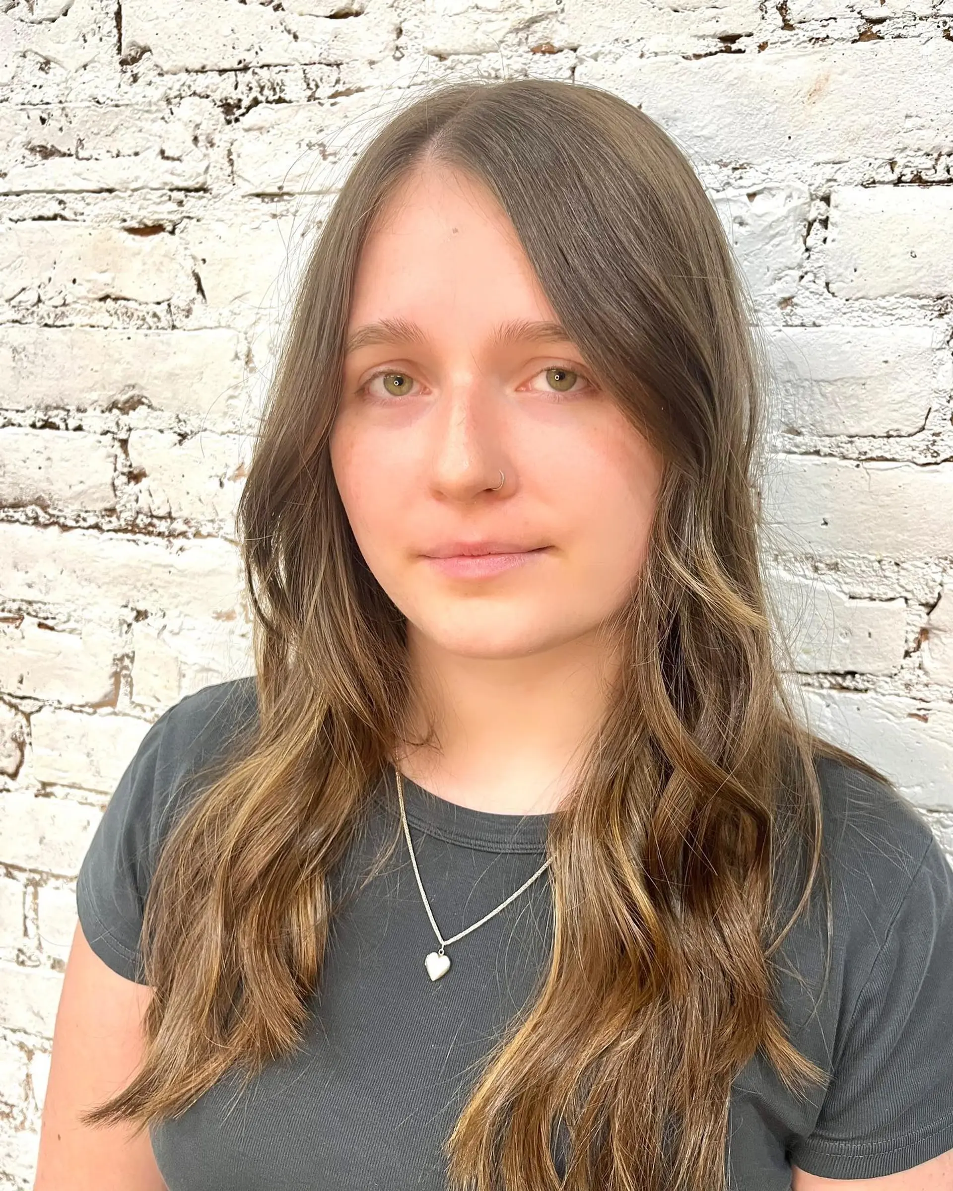 Long brown hair enhanced with soft, warm dimensional highlights and gentle face-framing waves. 1