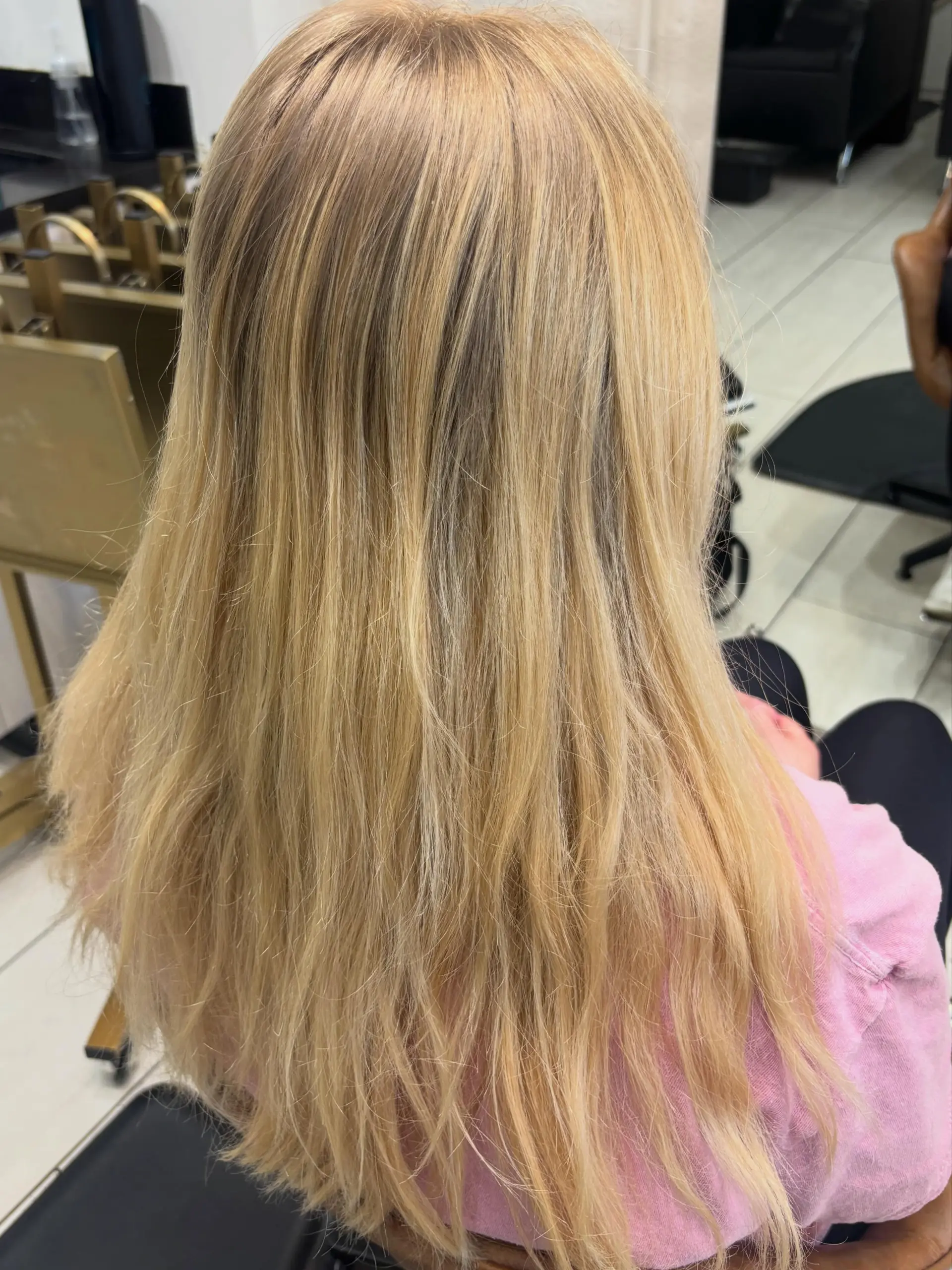 Long warm blonde hair with blended dimensional highlights styled straight down the back. 1