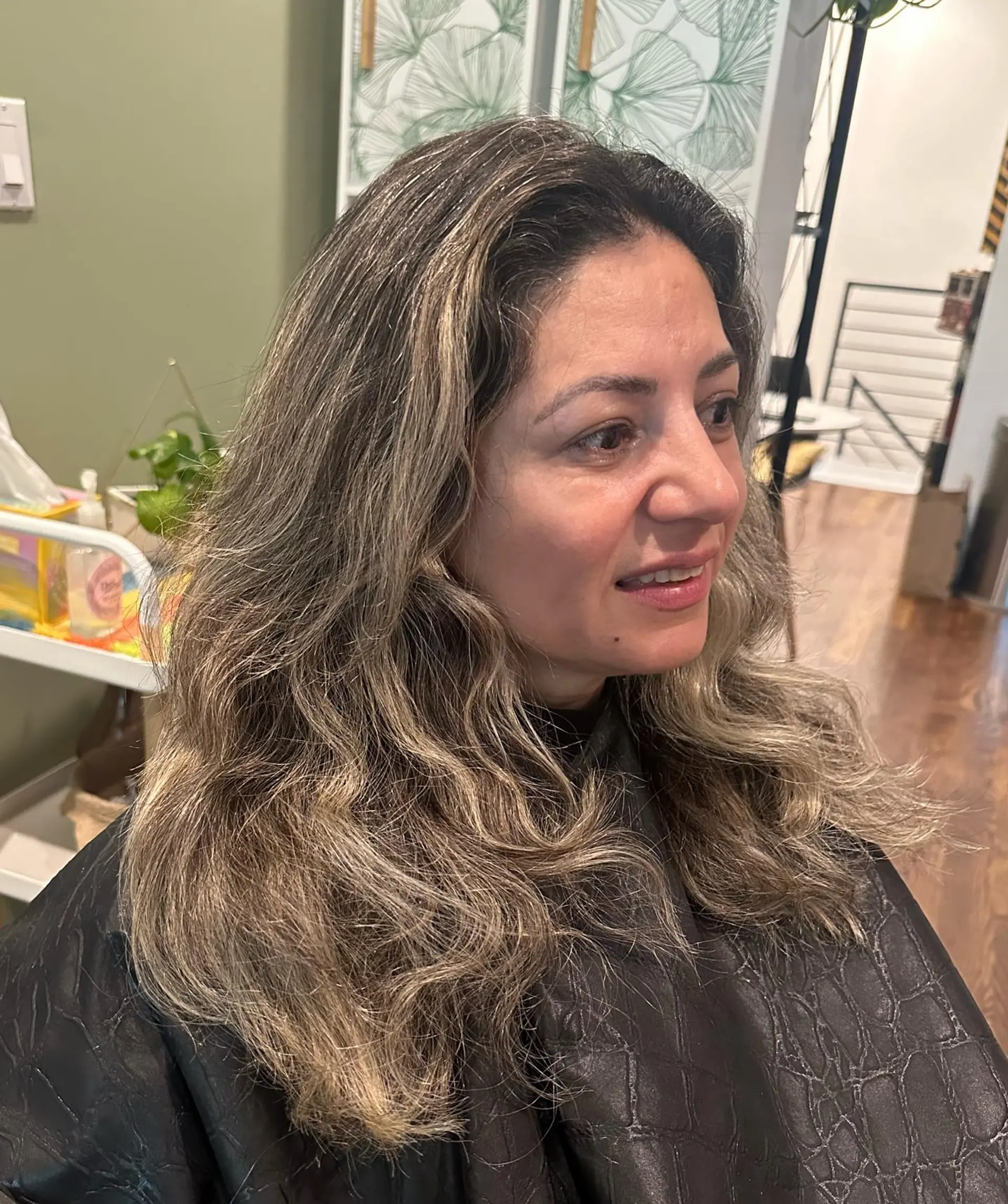 Long dark brown hair enhanced with fine ash blonde highlights, styled in soft, loose waves. 1
