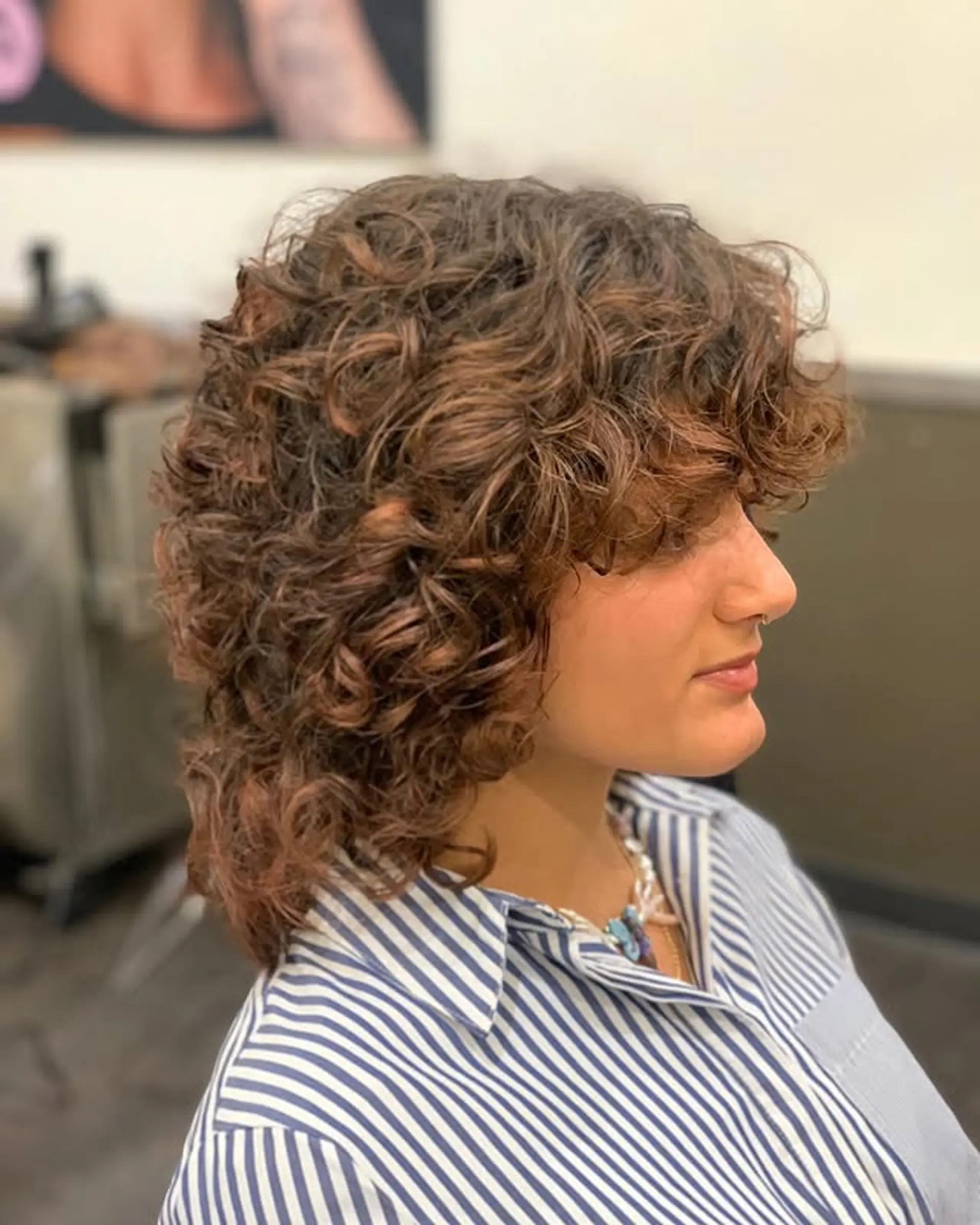 A modern shag haircut with bouncy curls and face-framing bangs. 1