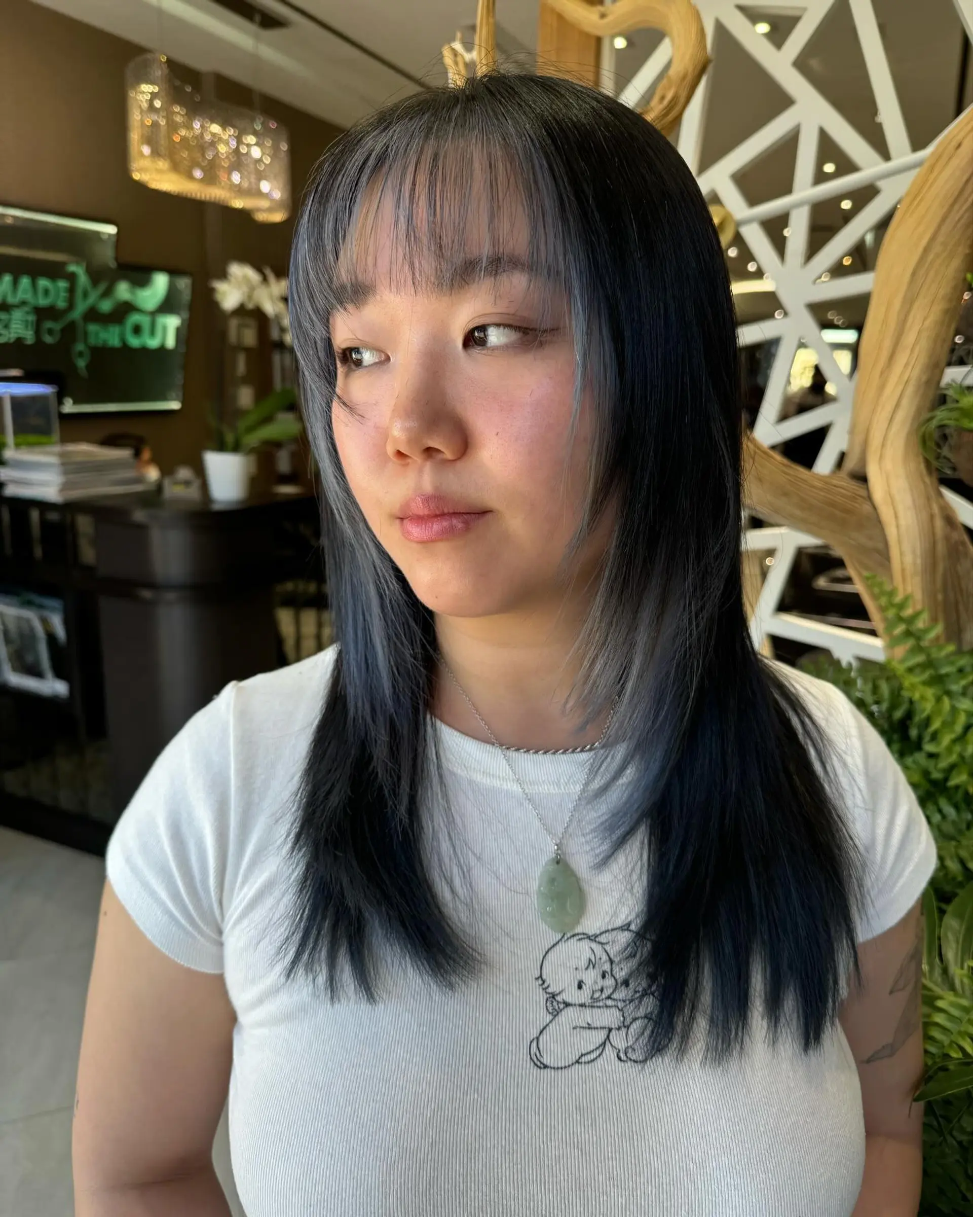This is a medium-length layered haircut with Korean bangs and gray face-framing highlights. 1