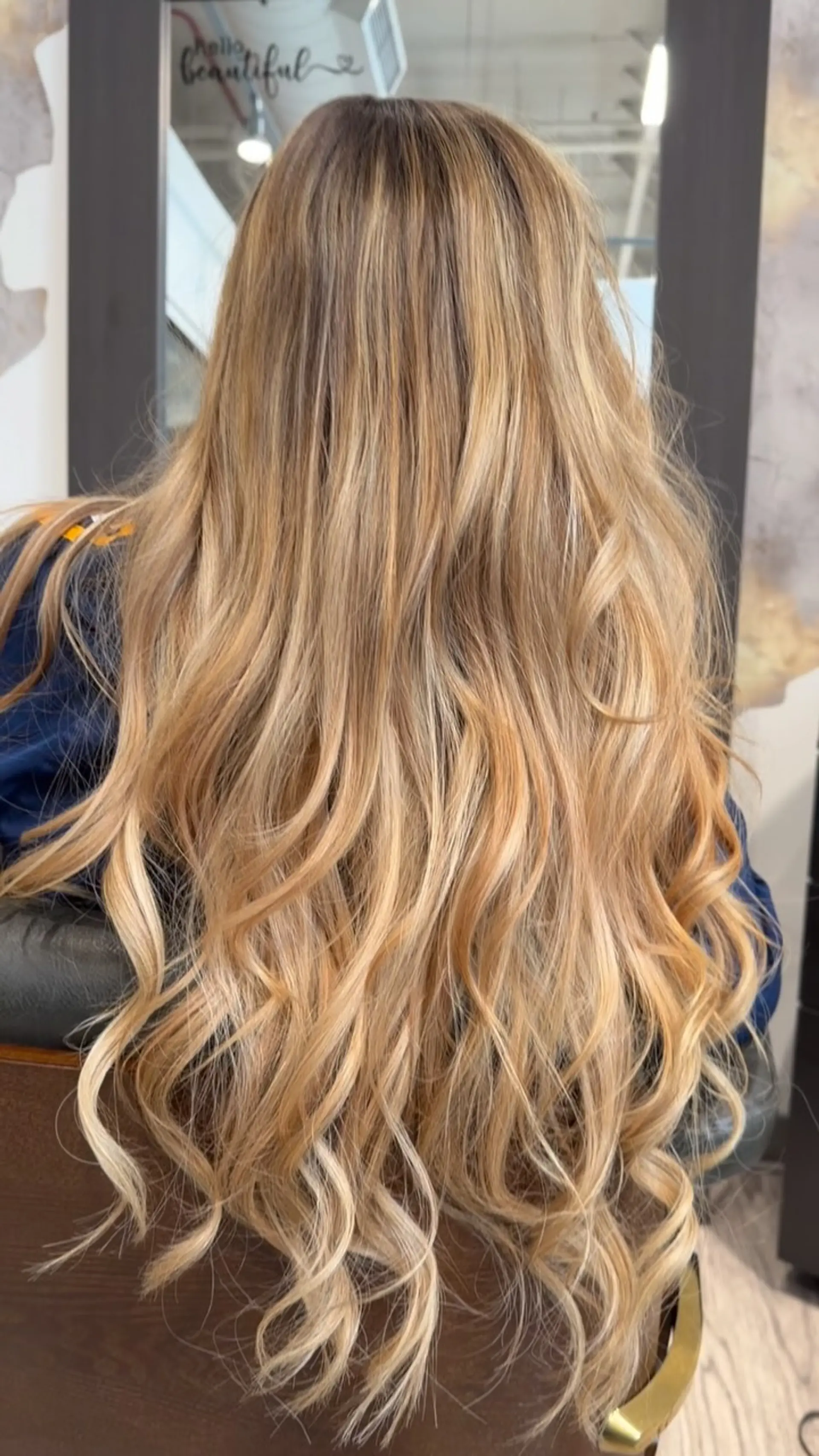 Long, dimensional warm blonde hair styled with soft, loose waves towards the ends. 1