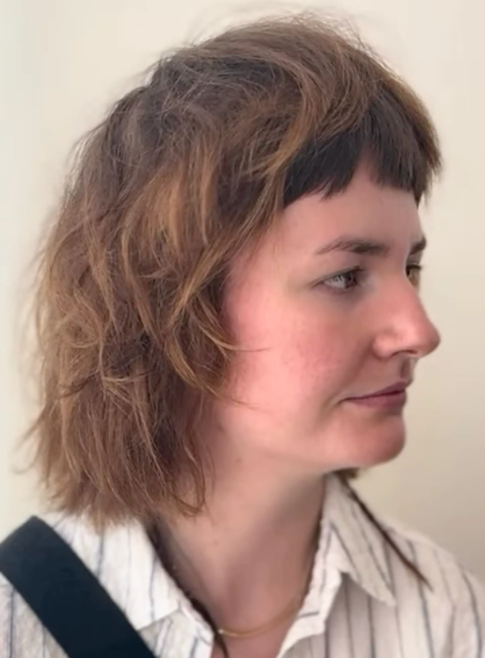 A wavy, medium-length hairstyle with brown and auburn tones, featuring choppy layers and short, edgy bangs, creating a natural, carefree look. 2