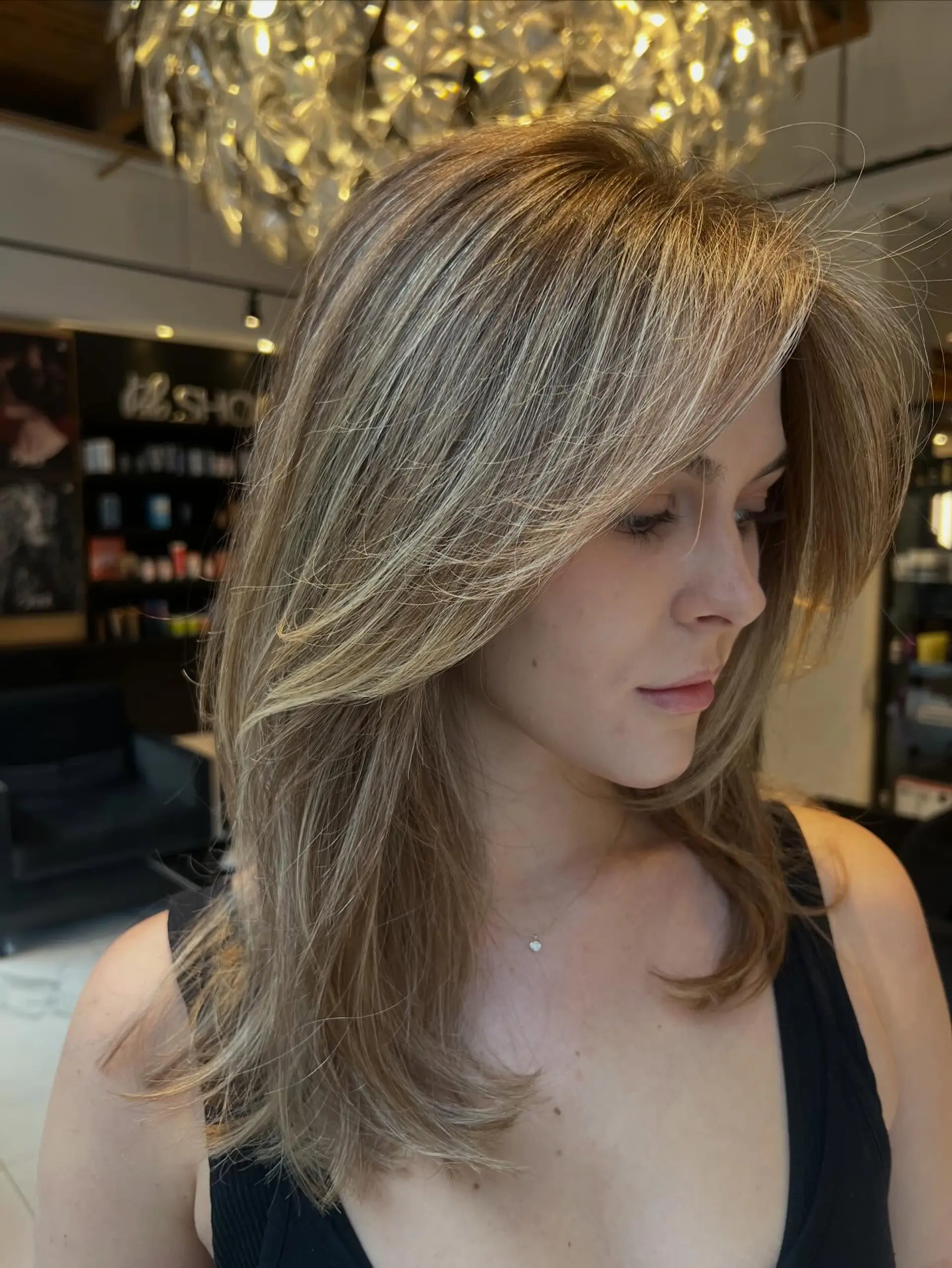 Long layered haircut with face-framing pieces and smooth blowout styling, featuring fine dimensional blonde highlights. 1