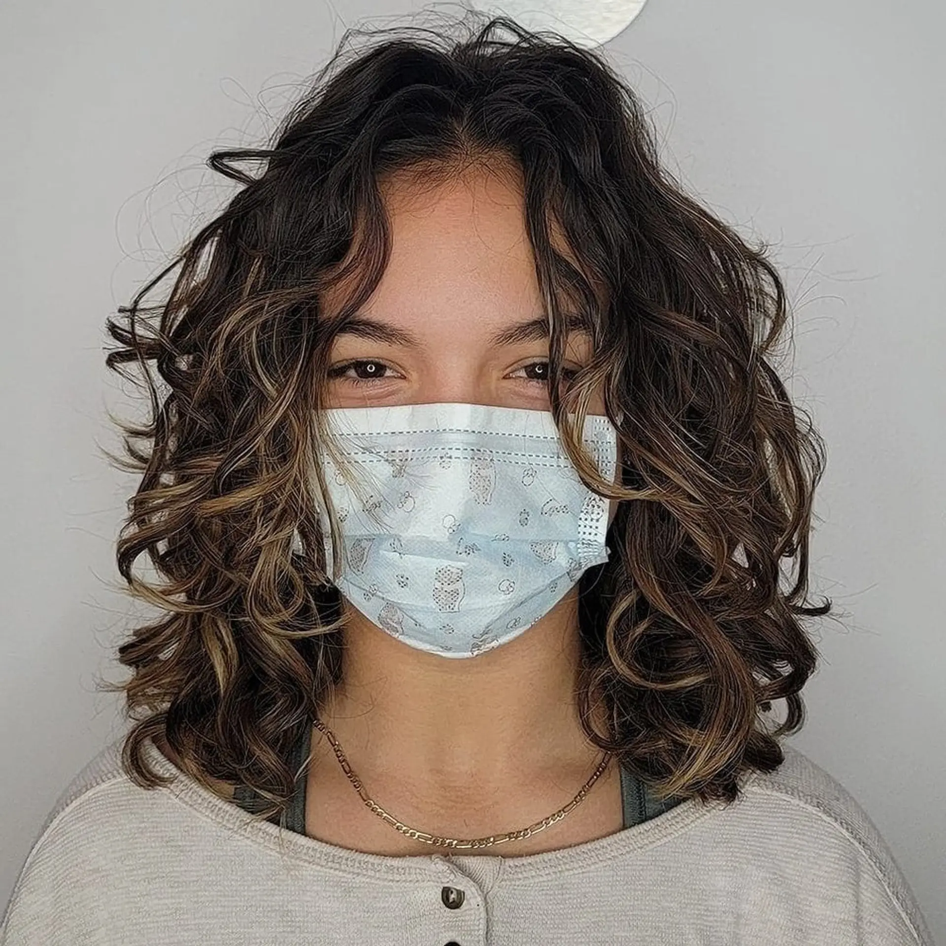 Medium-length curly hair with brown color and blonde highlights, showcasing a natural, voluminous, and dynamic look. 1