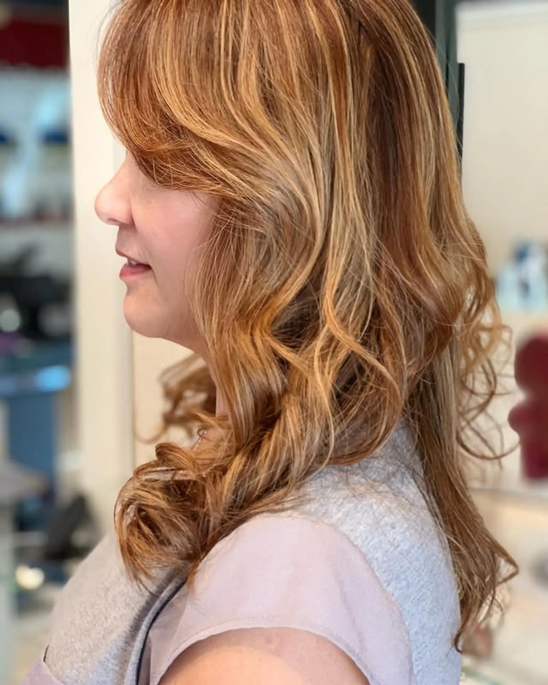 Long, layered hair styled with soft, voluminous waves, enhanced by face-framing curtain bangs. The overall look is effortless and chic, with movement and texture. 1