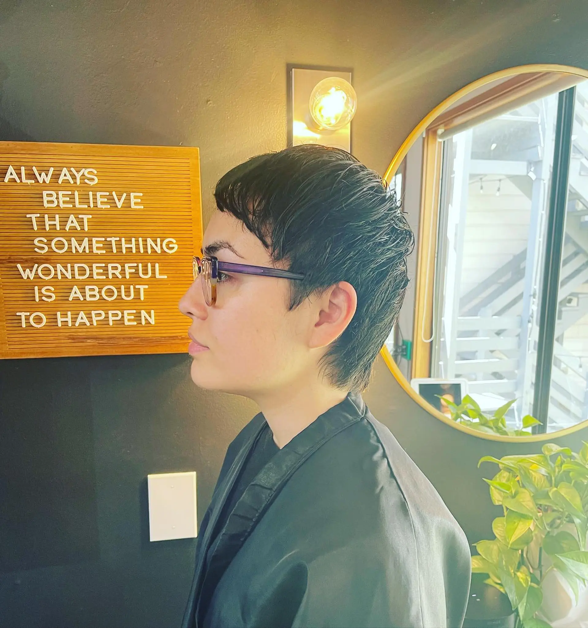 A textured dark pixie haircut featuring piecey micro bangs and softly tapered sides and nape. 1