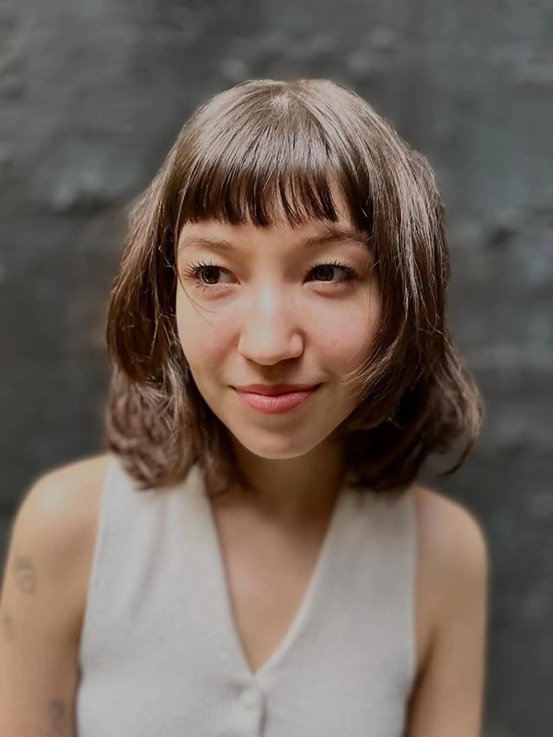 A shaggy, textured bob with short, blunt baby bangs and choppy layers for a modern, effortless look. 1