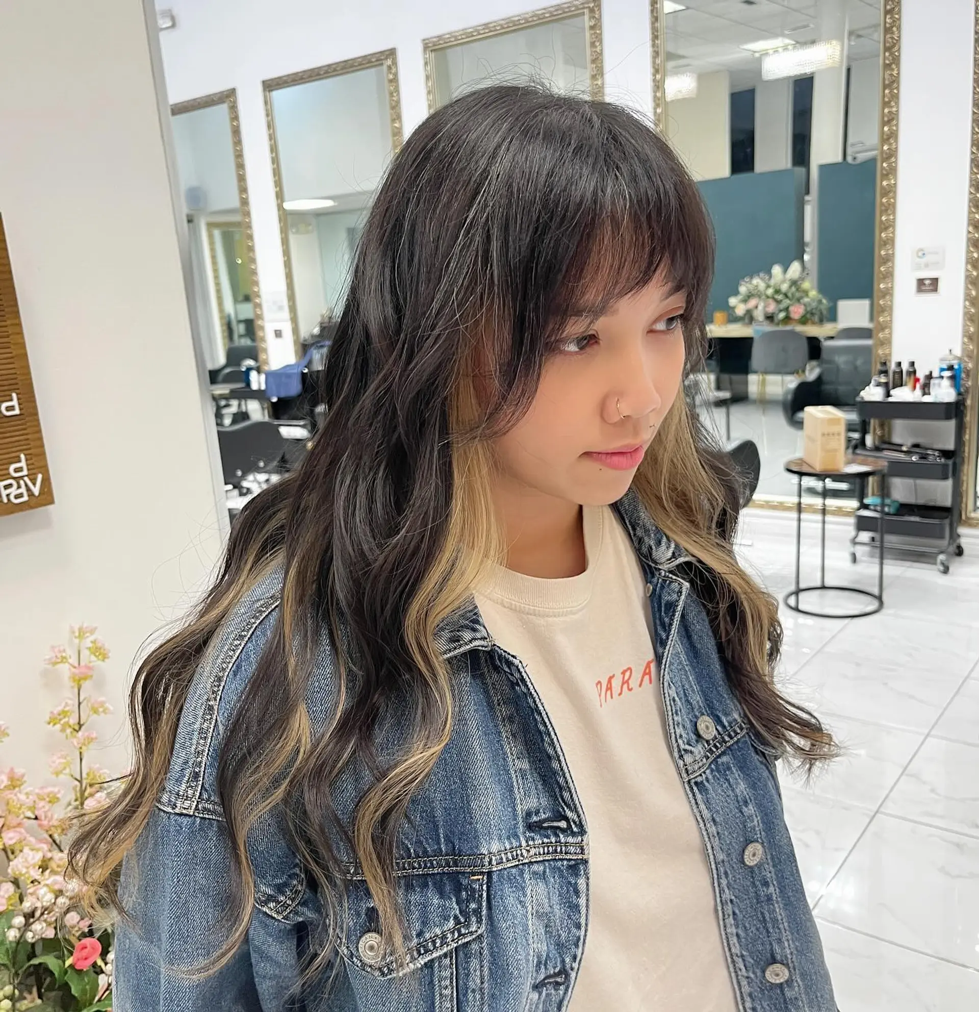Long dark wavy hair with contrasting blonde peekaboo highlights underneath and textured bangs. 1