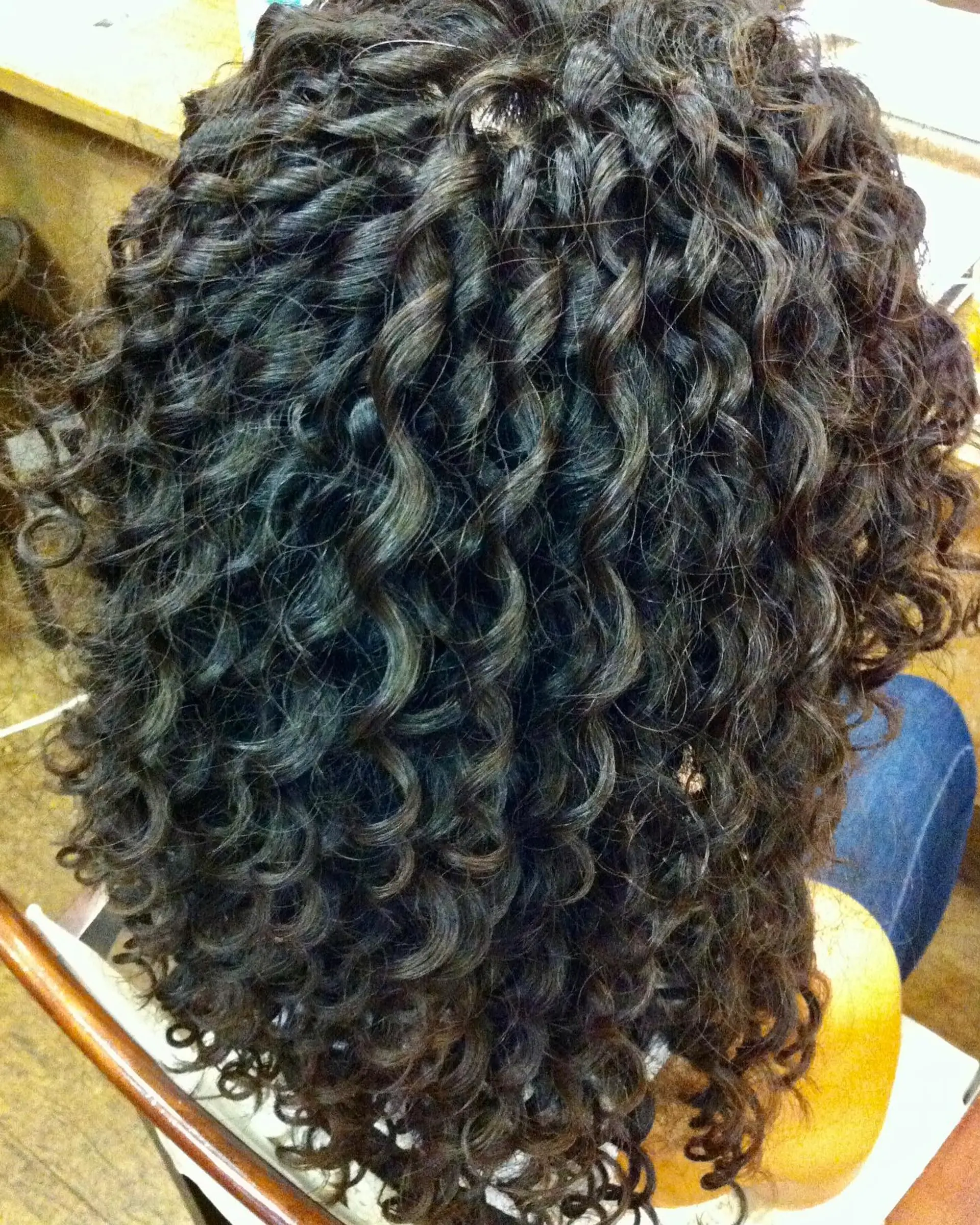 Medium-length dark hair styled with defined, voluminous tight spiral curls throughout. 1