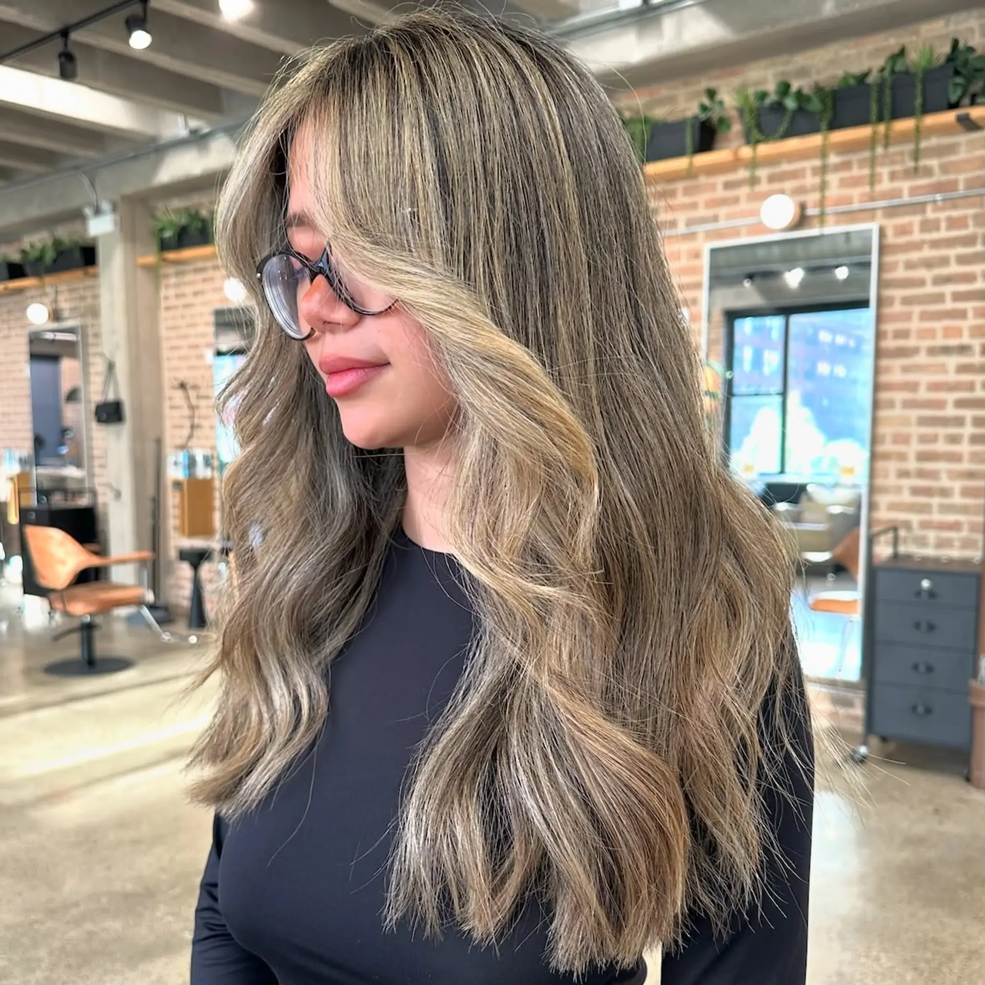 A long, layered hairstyle with a blended ash blonde balayage and face-framing layers. 1
