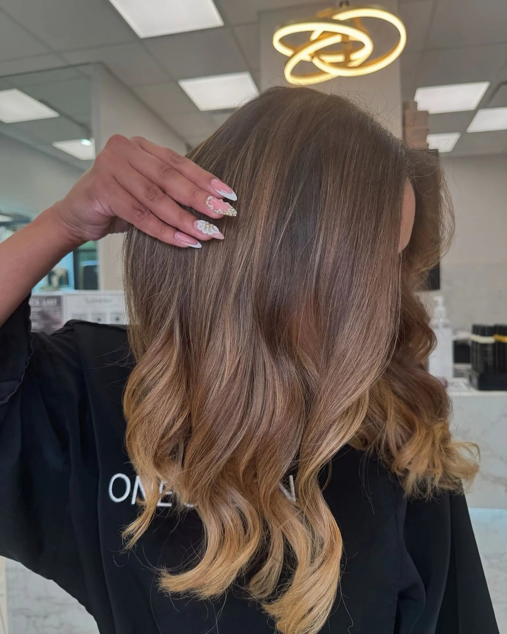 Long, wavy hair with an ombre transition from bronze brunette to warm blonde, featuring soft waves and subtle layers.

Color by Laura
Cut by Dr. Balayage
