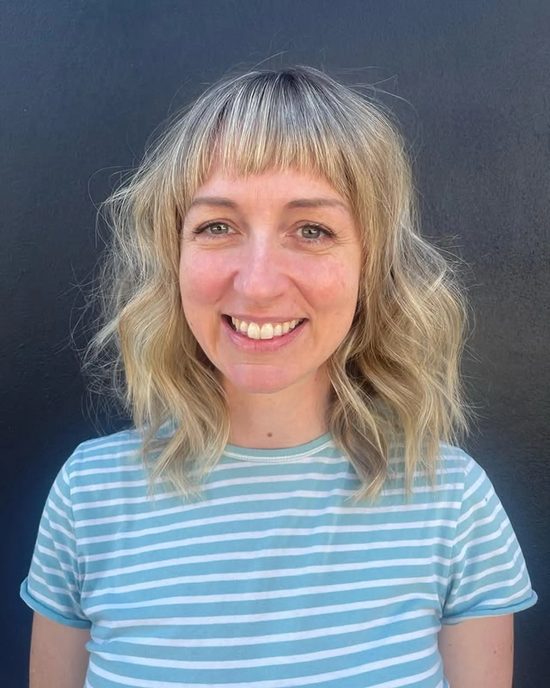 A trendy wavy shag haircut with short, micro bangs and lots of layers. 1