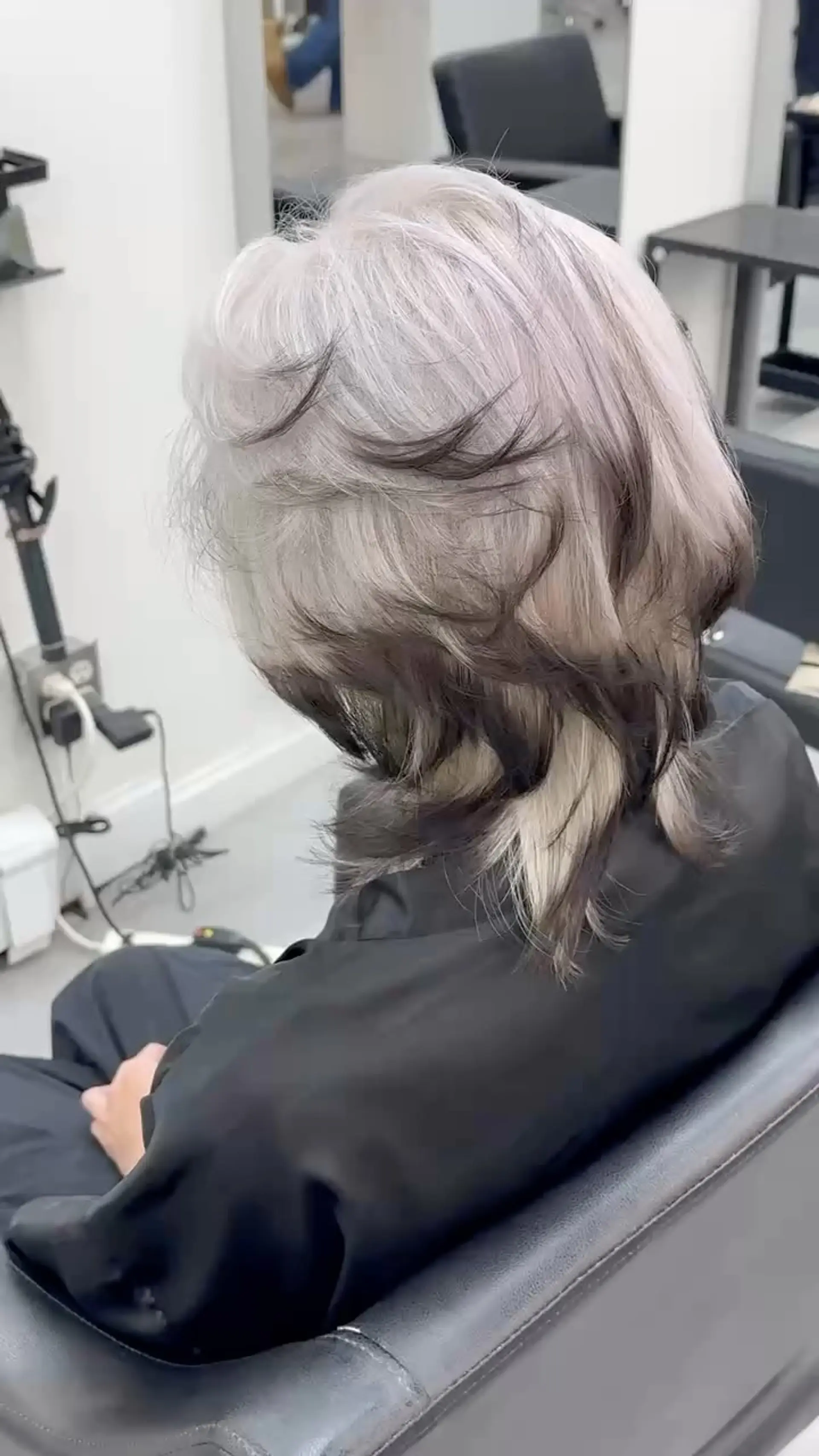 A textured layered wolf cut featuring ash silver tones contrasted with dark underlayers and feathered ends. 1