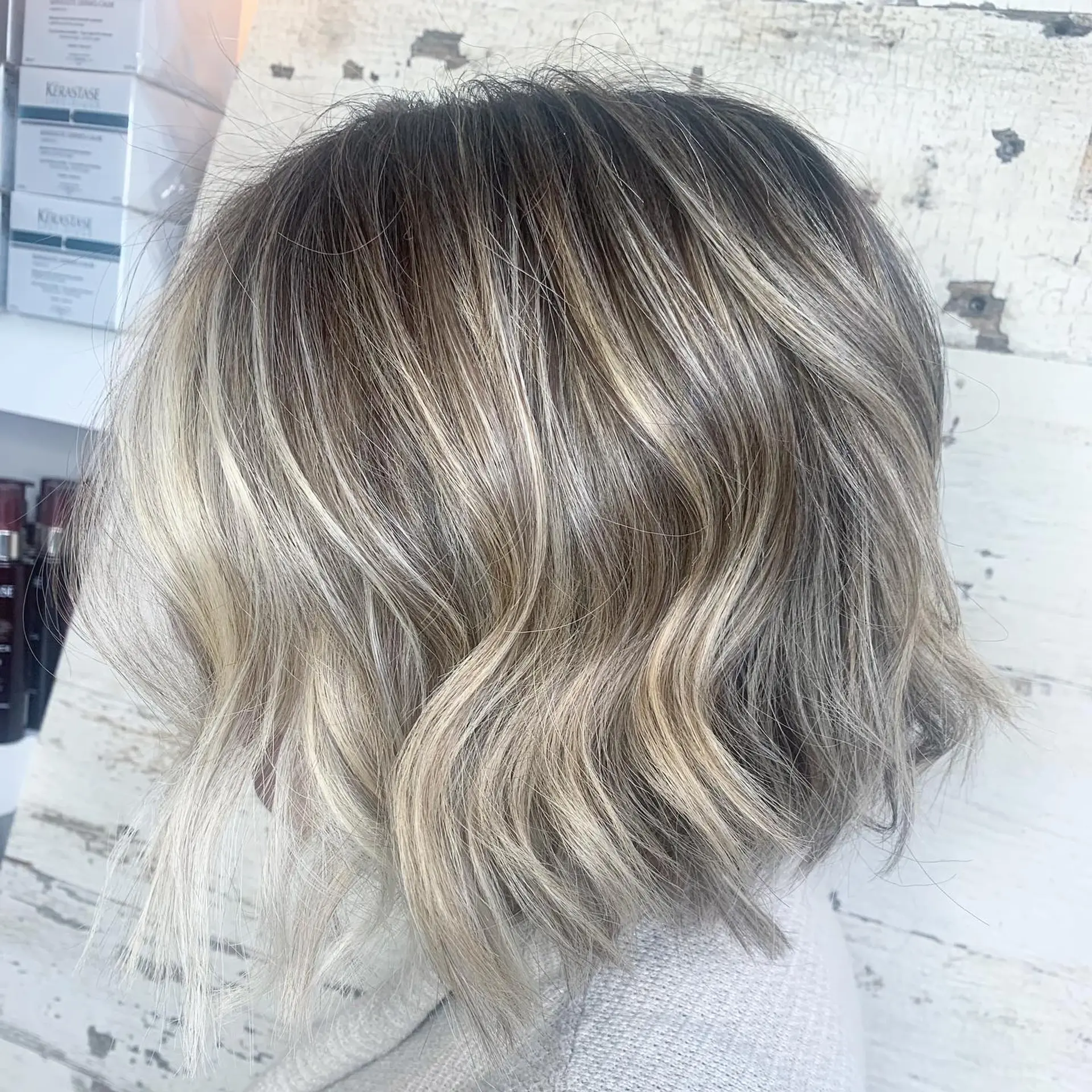 A textured chin-length bob cut styled in relaxed, beachy waves with dimensional cool blonde balayage and a soft shadow root. 1
