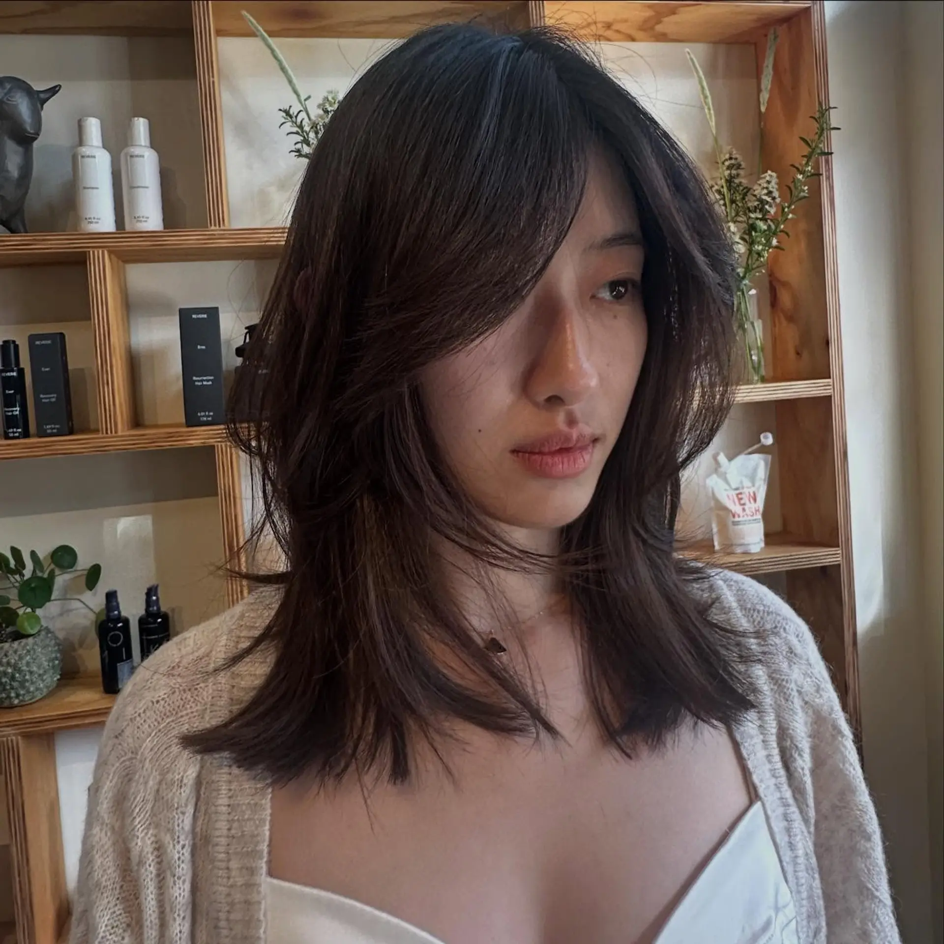 Medium-length dark brown hair styled with soft textured layers and face-framing curtain bangs. 1