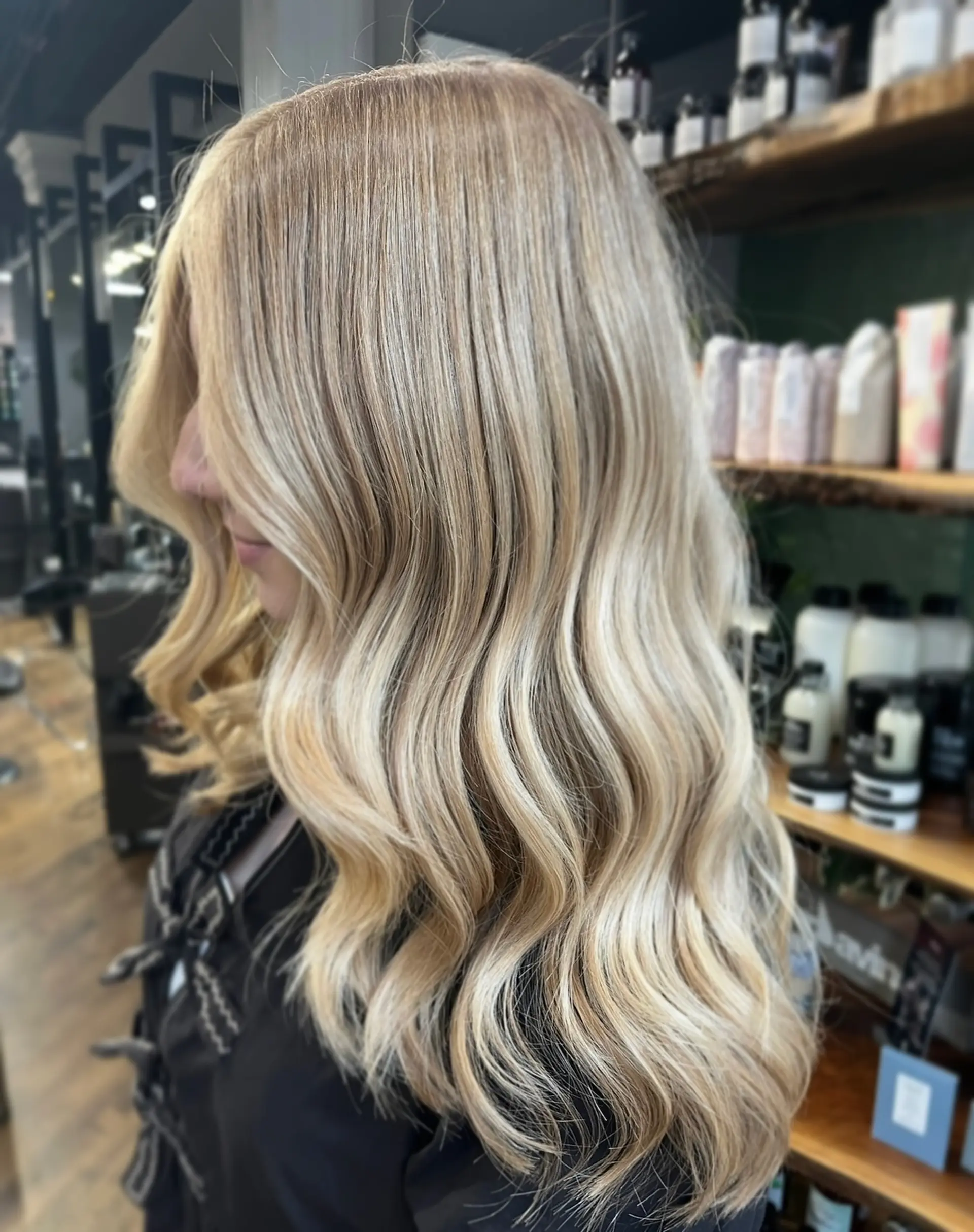 Seamless dimensional blonde hair styled in soft, glossy waves cascading past the shoulders. 1