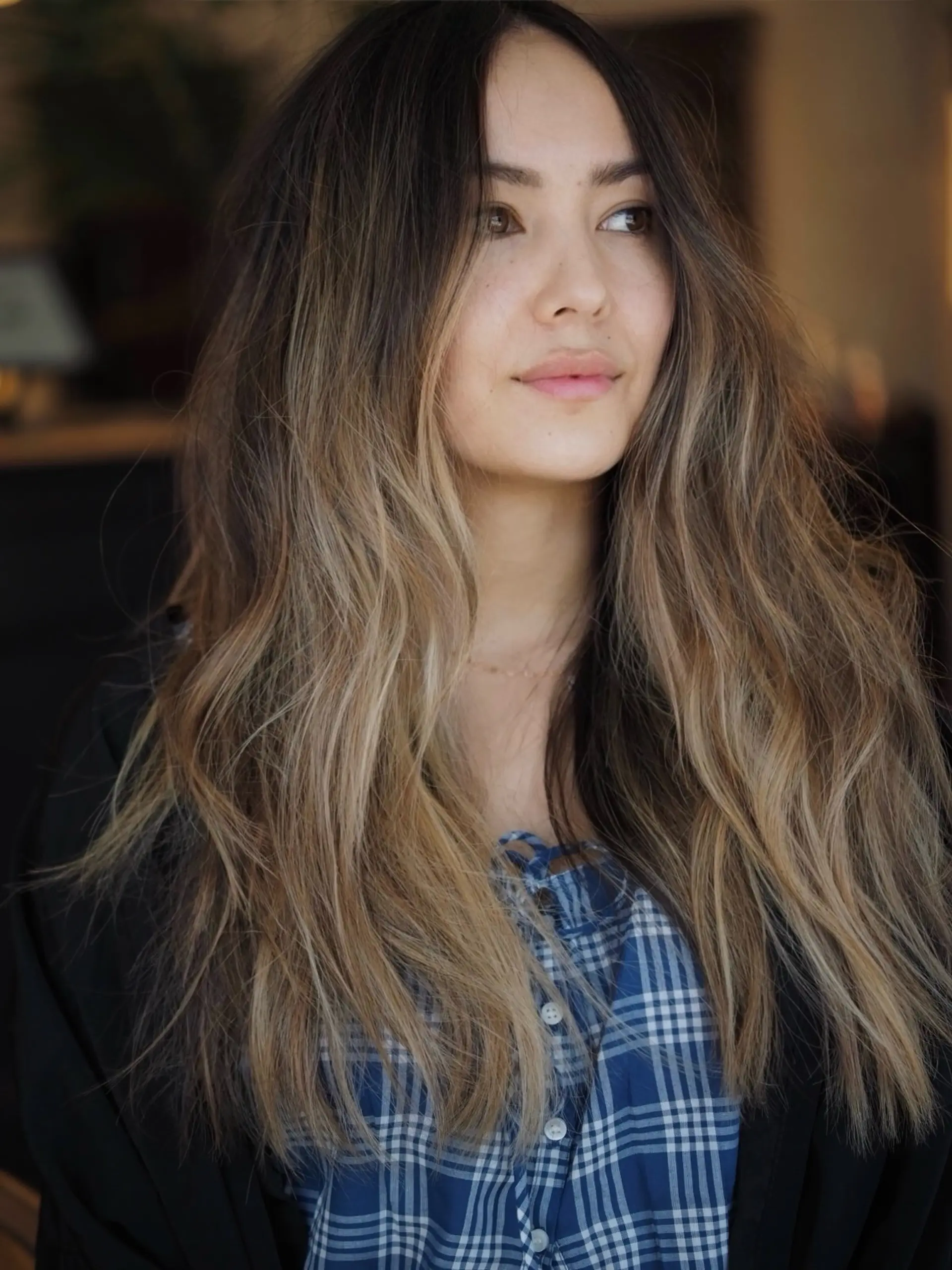 Long brunette hair brightened with dimensional sun-kissed blonde highlights, styled in soft, cascading waves. 1