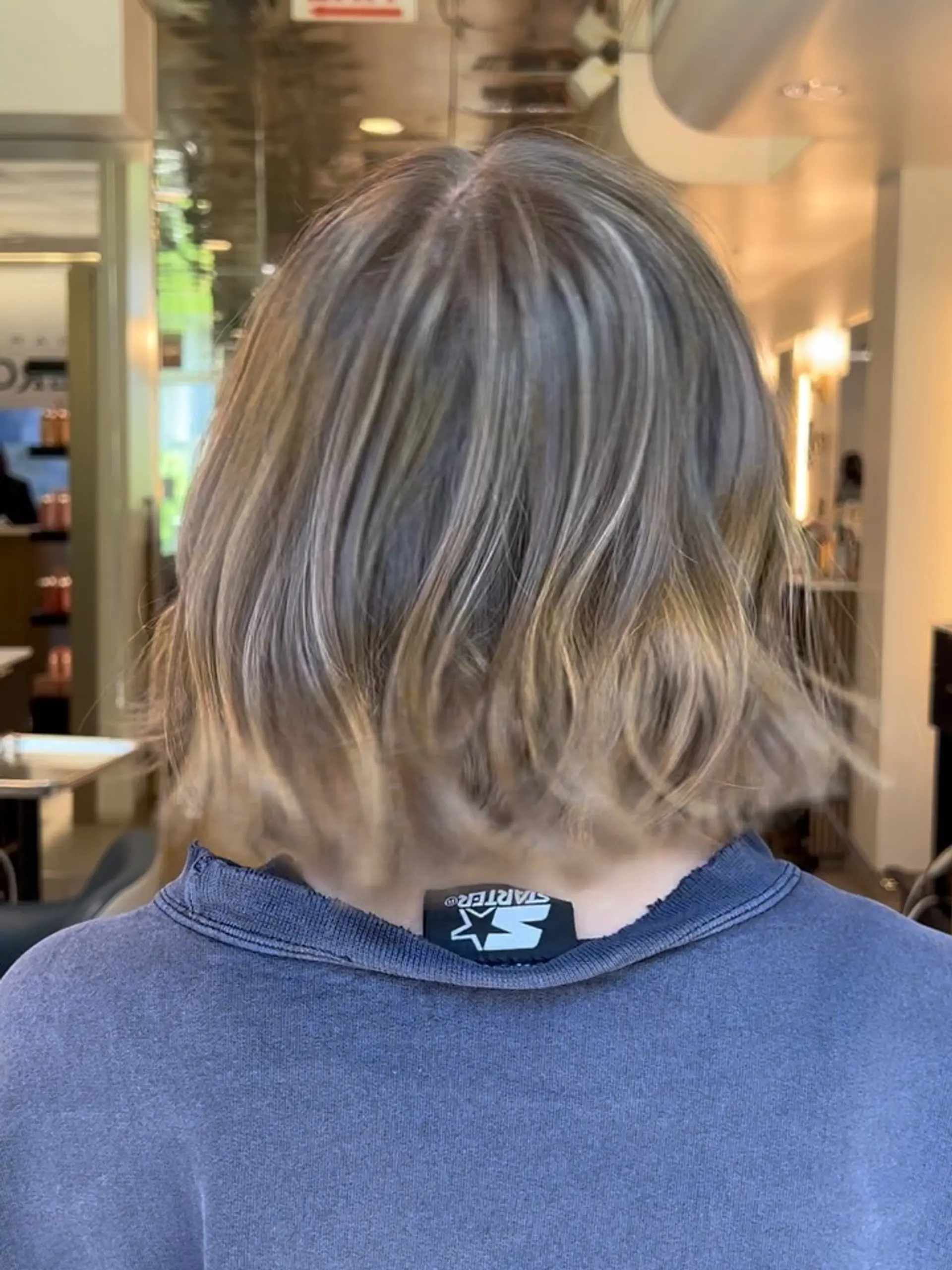 A textured neck-length bob cut featuring dimensional cool-toned blonde highlights over a light brown base. 1