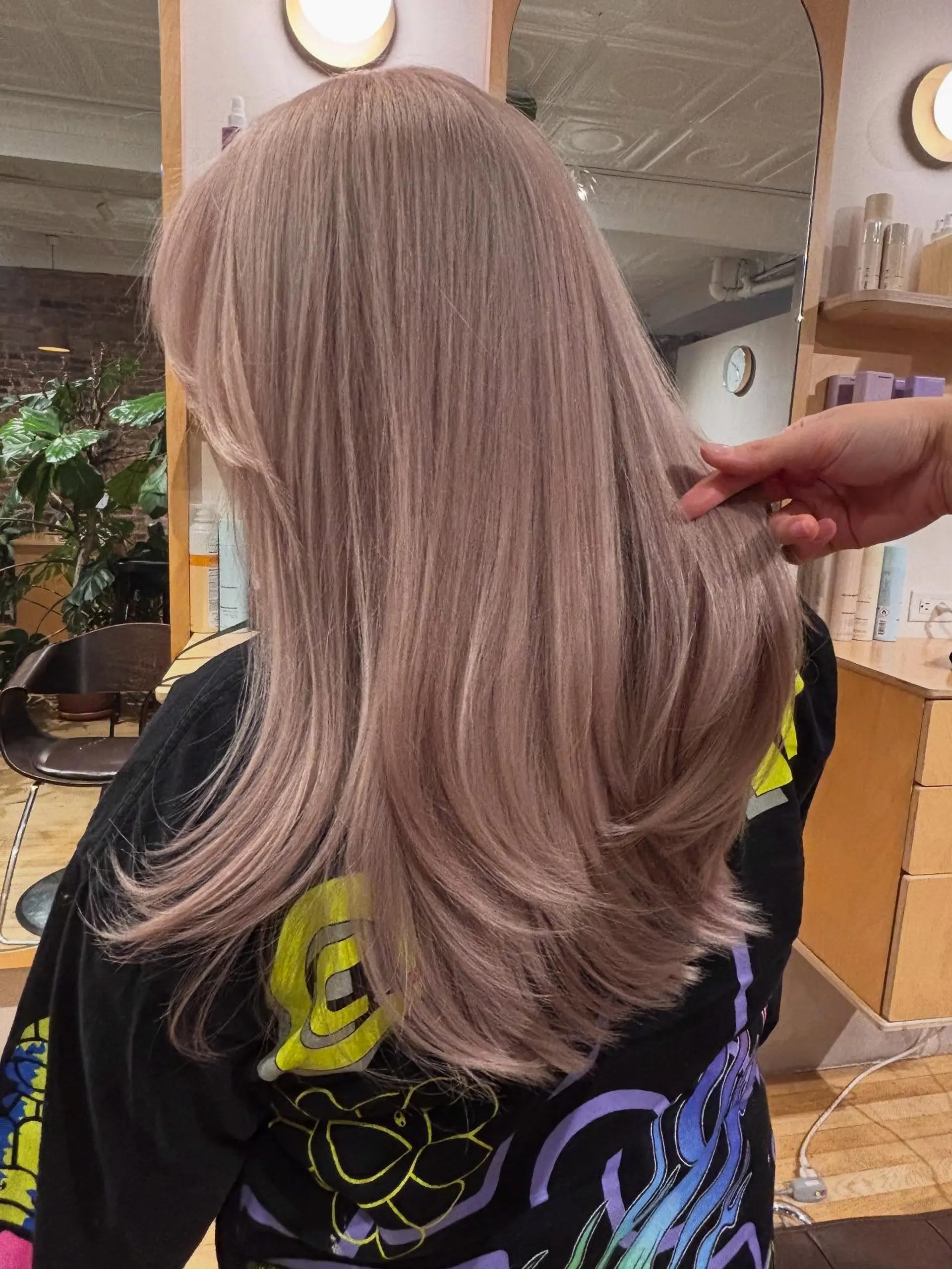 Long layered hair colored in a soft dusty pastel pink, styled with a smooth blowout and gently curved ends. 1