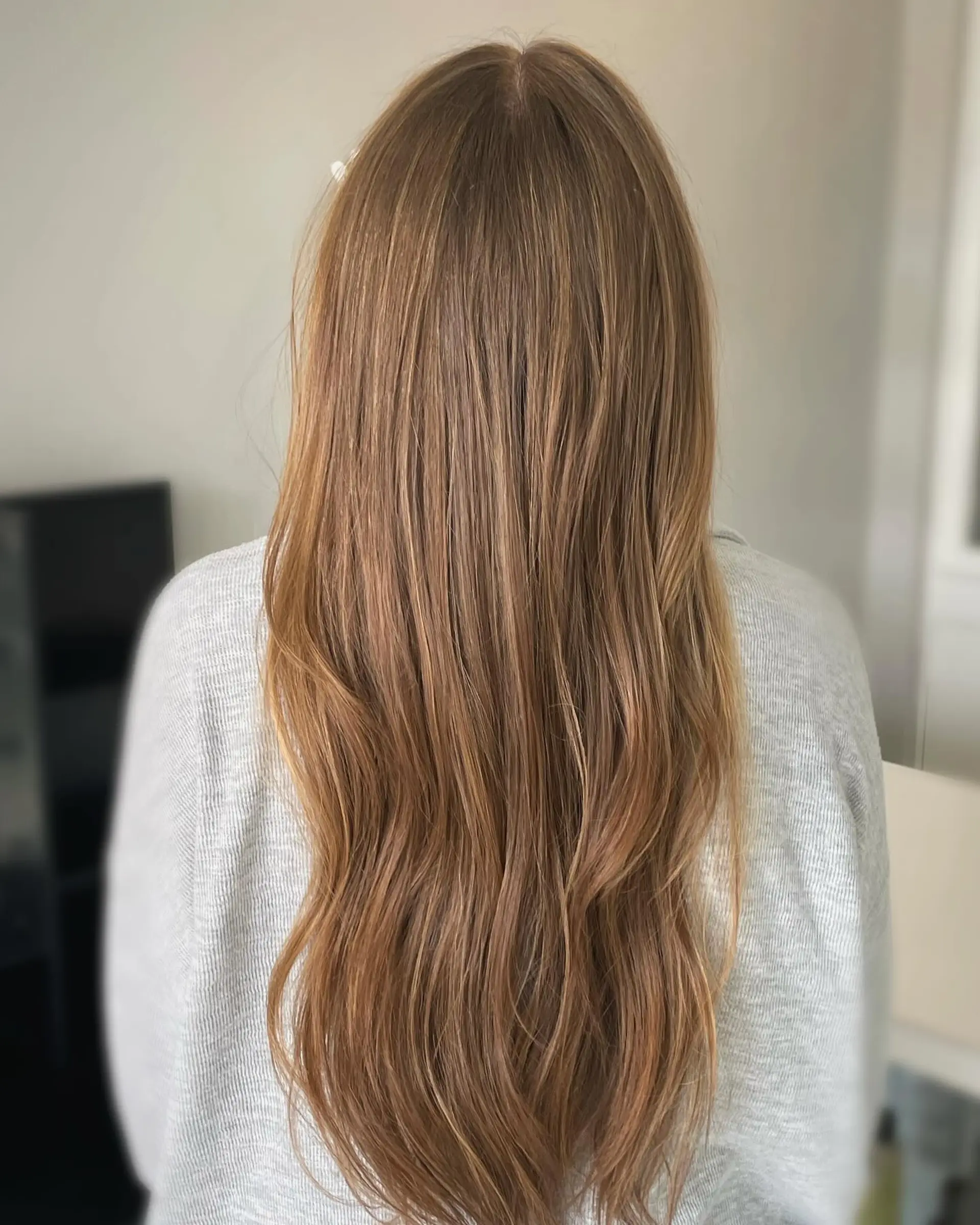 Long cascading light brown hair styled with subtle, natural-looking honey blonde highlights and soft, gentle waves through the lengths. 1