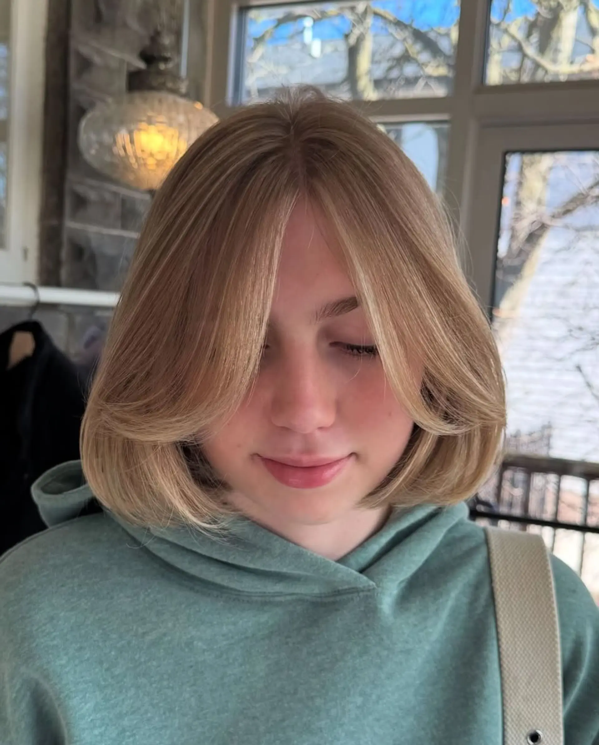 A rounded, neck-length bob styled with a voluminous blowout, feathered layers, and sweeping curtain bangs framing the face. 1