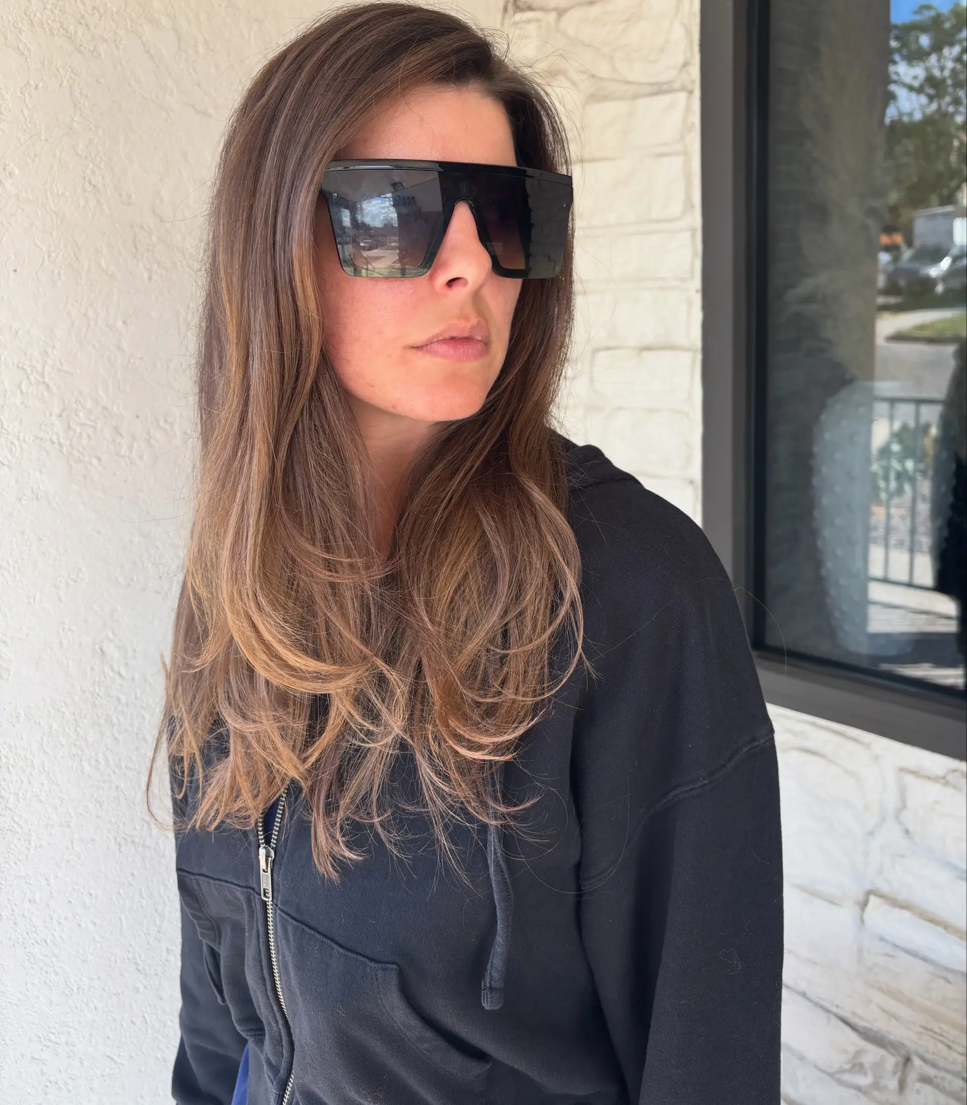Long layered brunette hair with subtle, natural-toned lighter brown balayage highlights styled with soft curved ends. 1