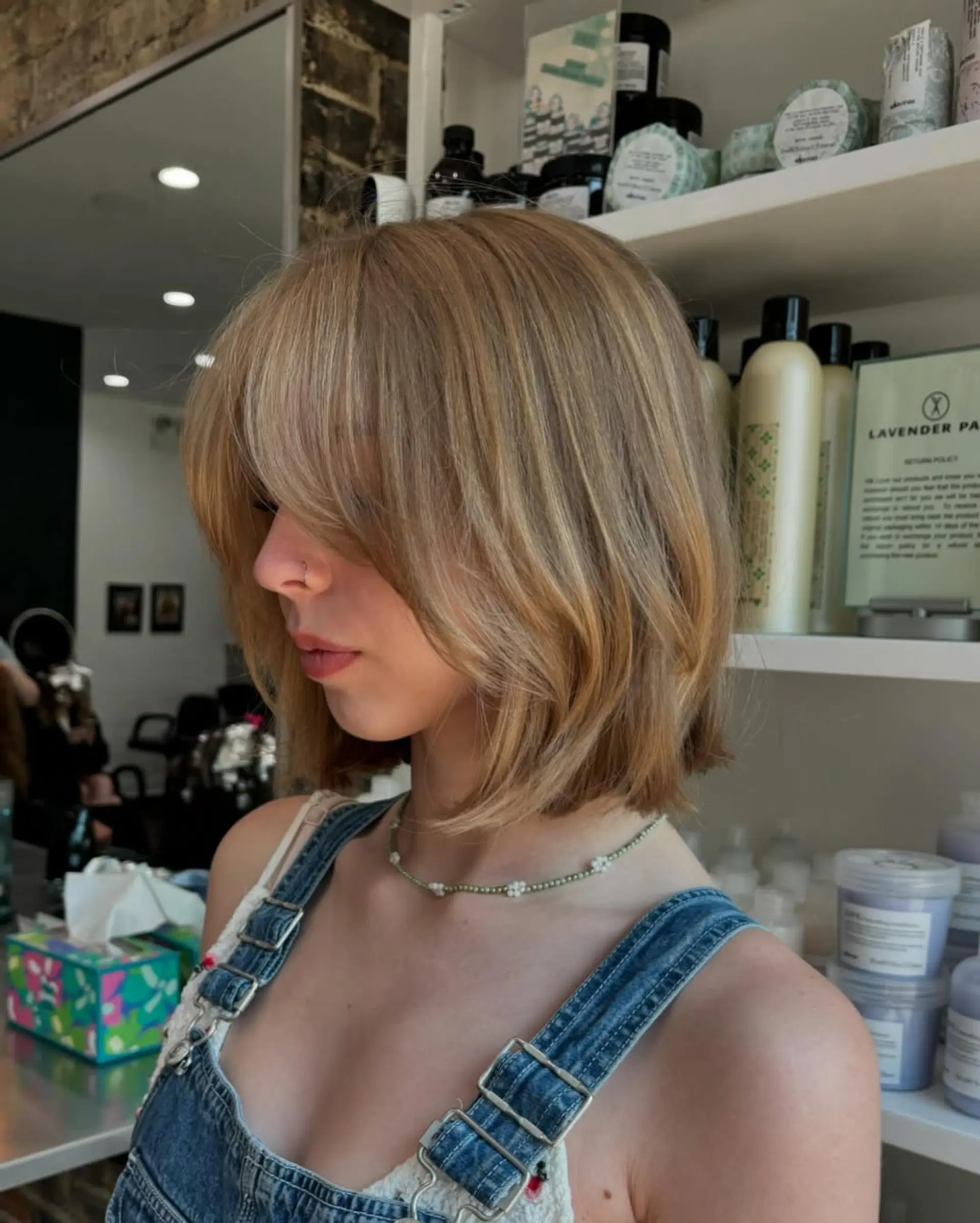 A chic, short, layered bob haircut featuring soft curtain bangs and face-framing layers for a modern and bouncy look. The length sits just above the shoulders, creating a fresh and youthful silhouette. 1