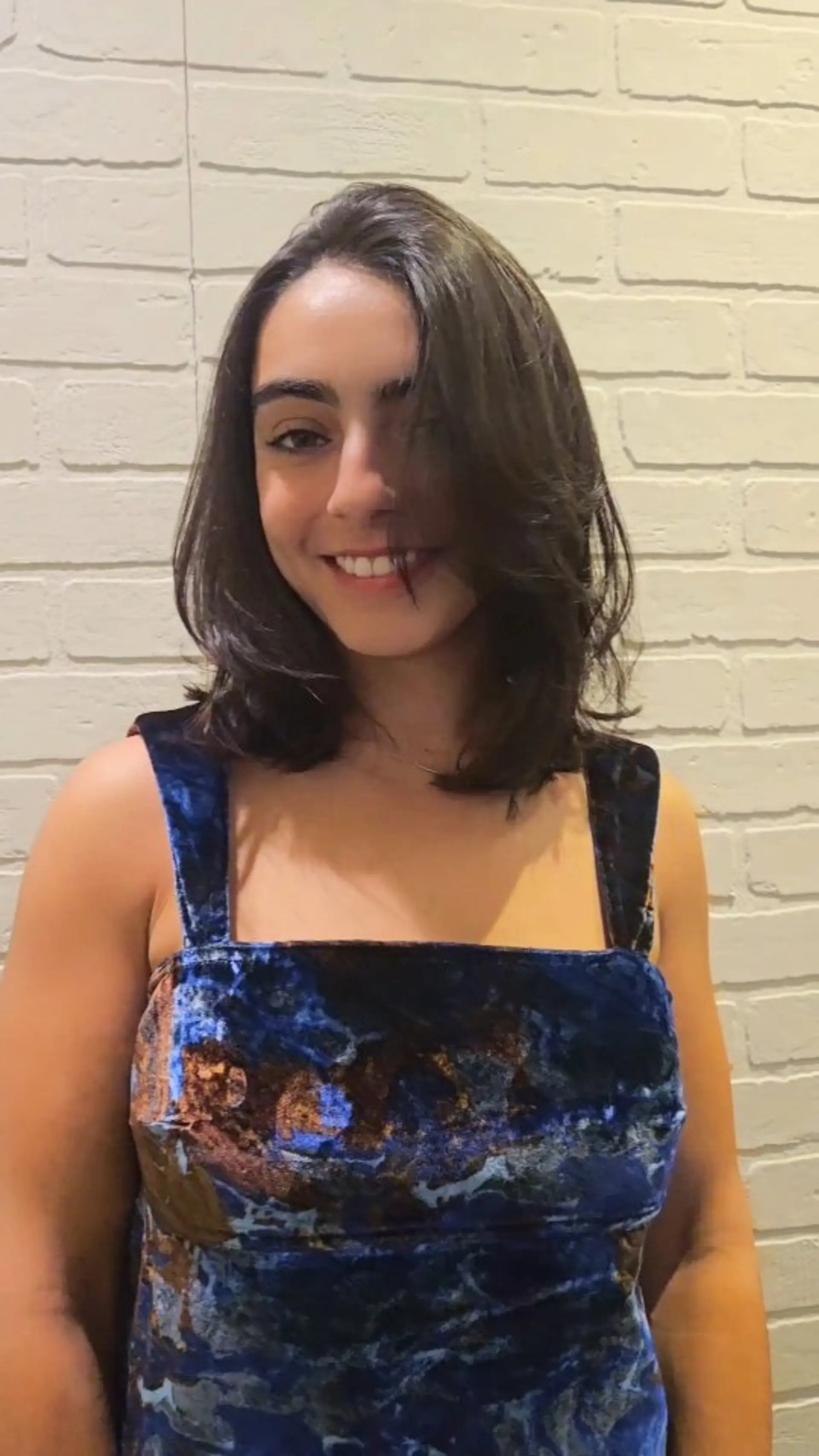 A medium-length dark haircut falling around the collarbones, styled with soft interior layers and face-framing swept bangs. 1