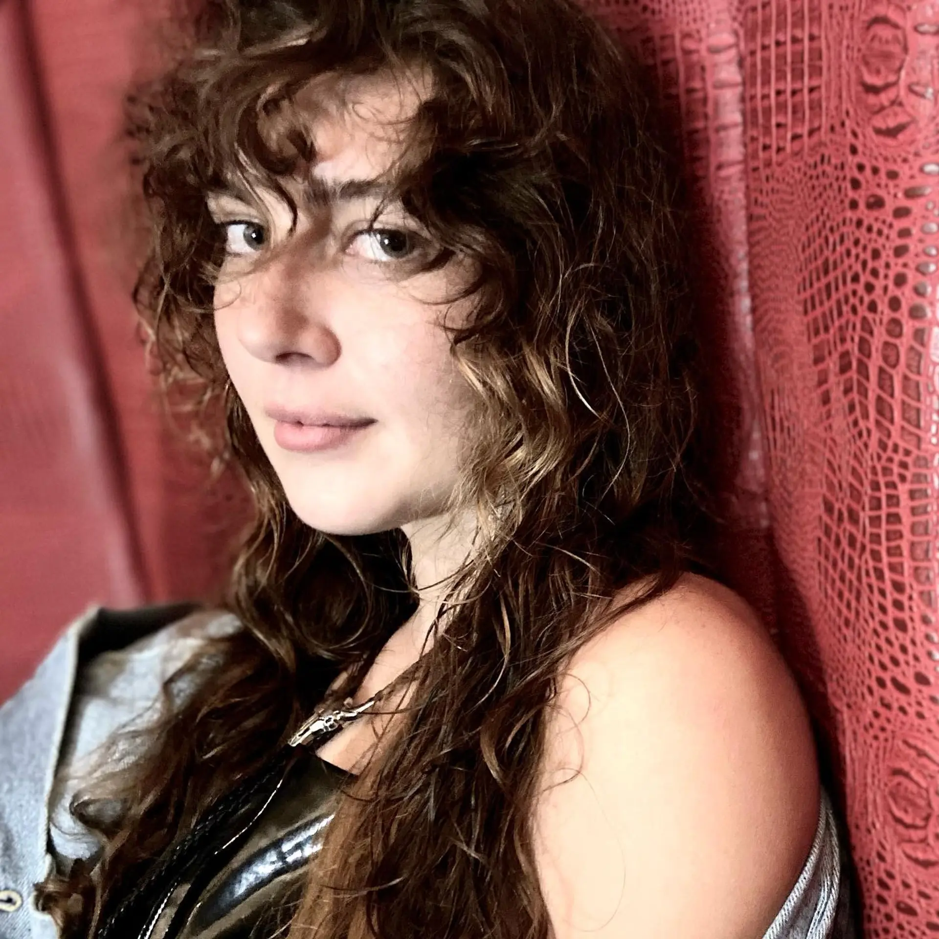 Long, layered curly hair with bangs and subtle balayage. 2