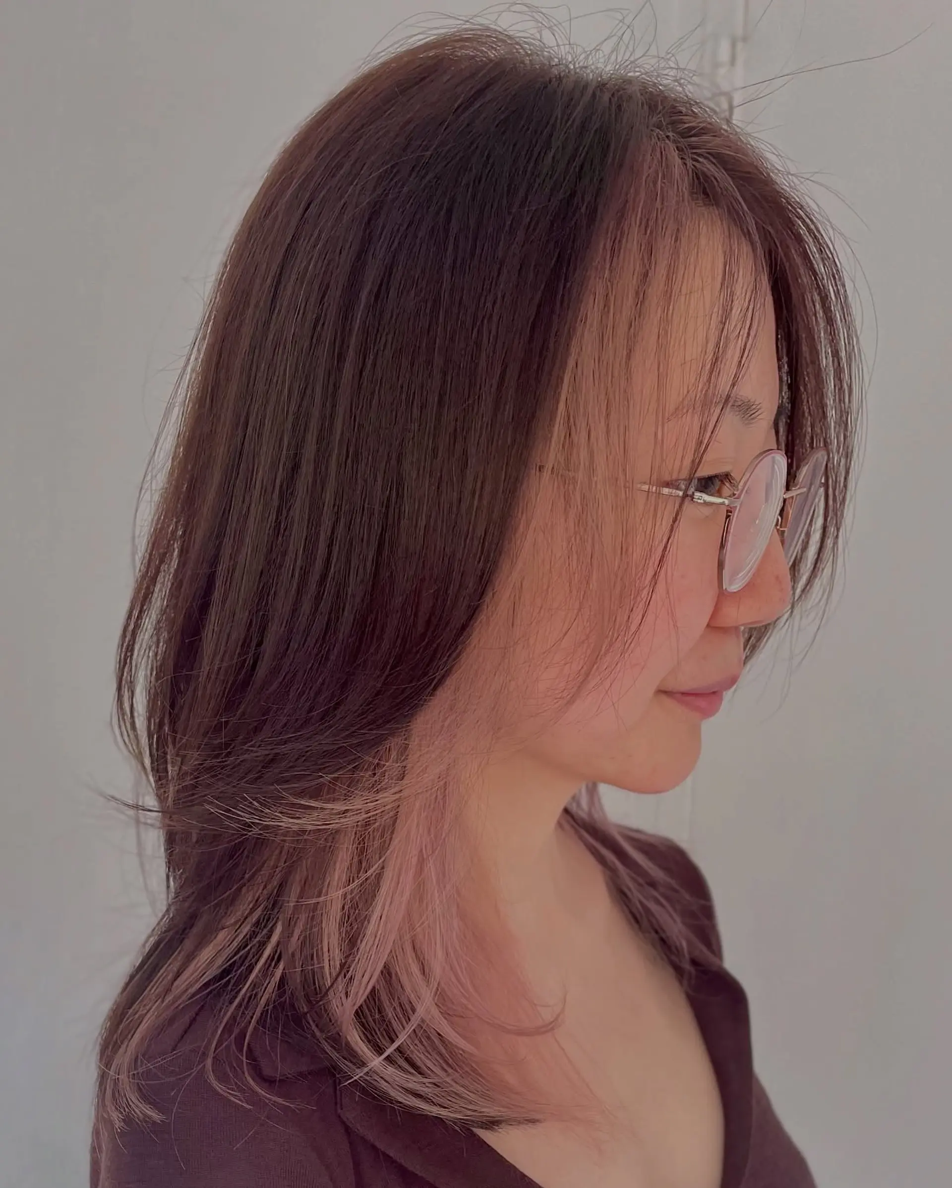 A medium-length layered cut featuring a natural brown base with soft pastel pink face-framing inner highlights. 1